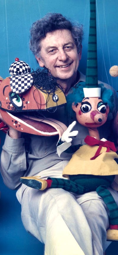 Photo of Norman Hetherington sitting down with his puppets and smiling at camera