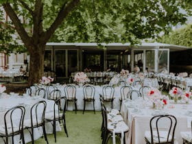 High tea tables set in a leafy hedged garden with a pavilion in the background