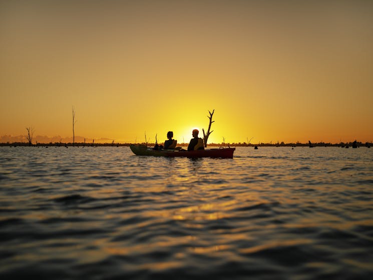Kayakers sitting on lake mulwala with stunning orange sunset behind them