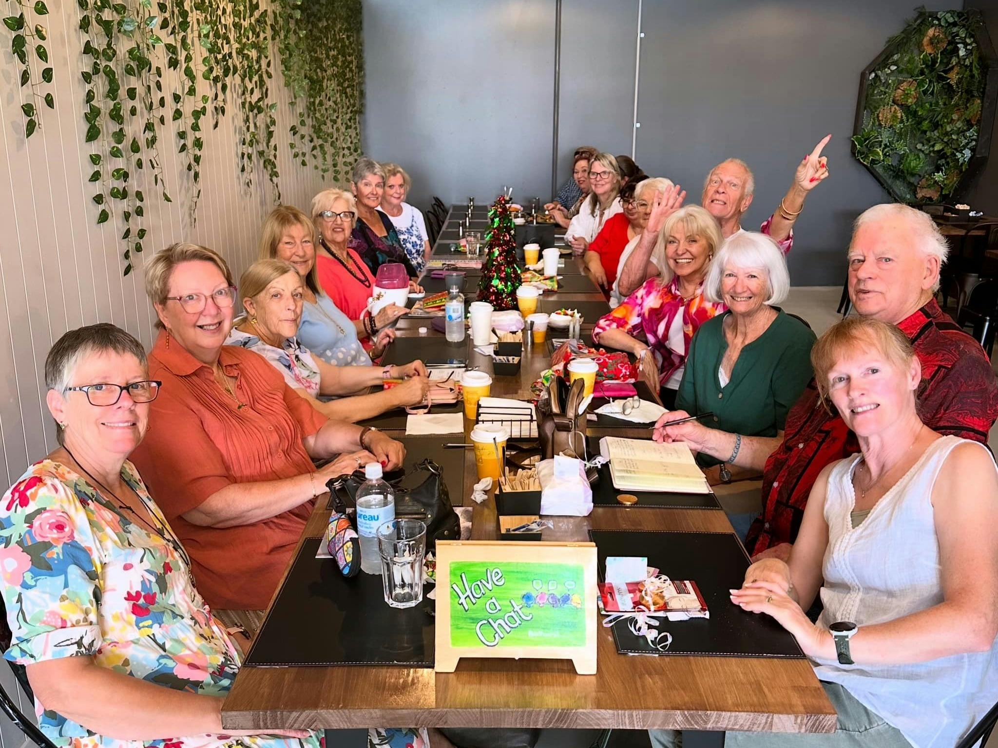 A large group of adults gathered around a table during a visit to The Coven Bx in Bathurst.