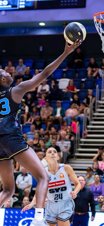 UC Capitals player driving to the basket for a layup during a WNBL game.