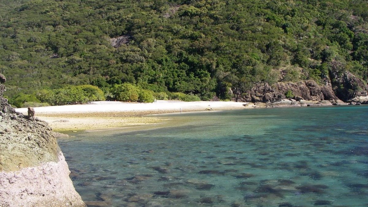 A small beach along the calm waters with rugged hills surrounding it