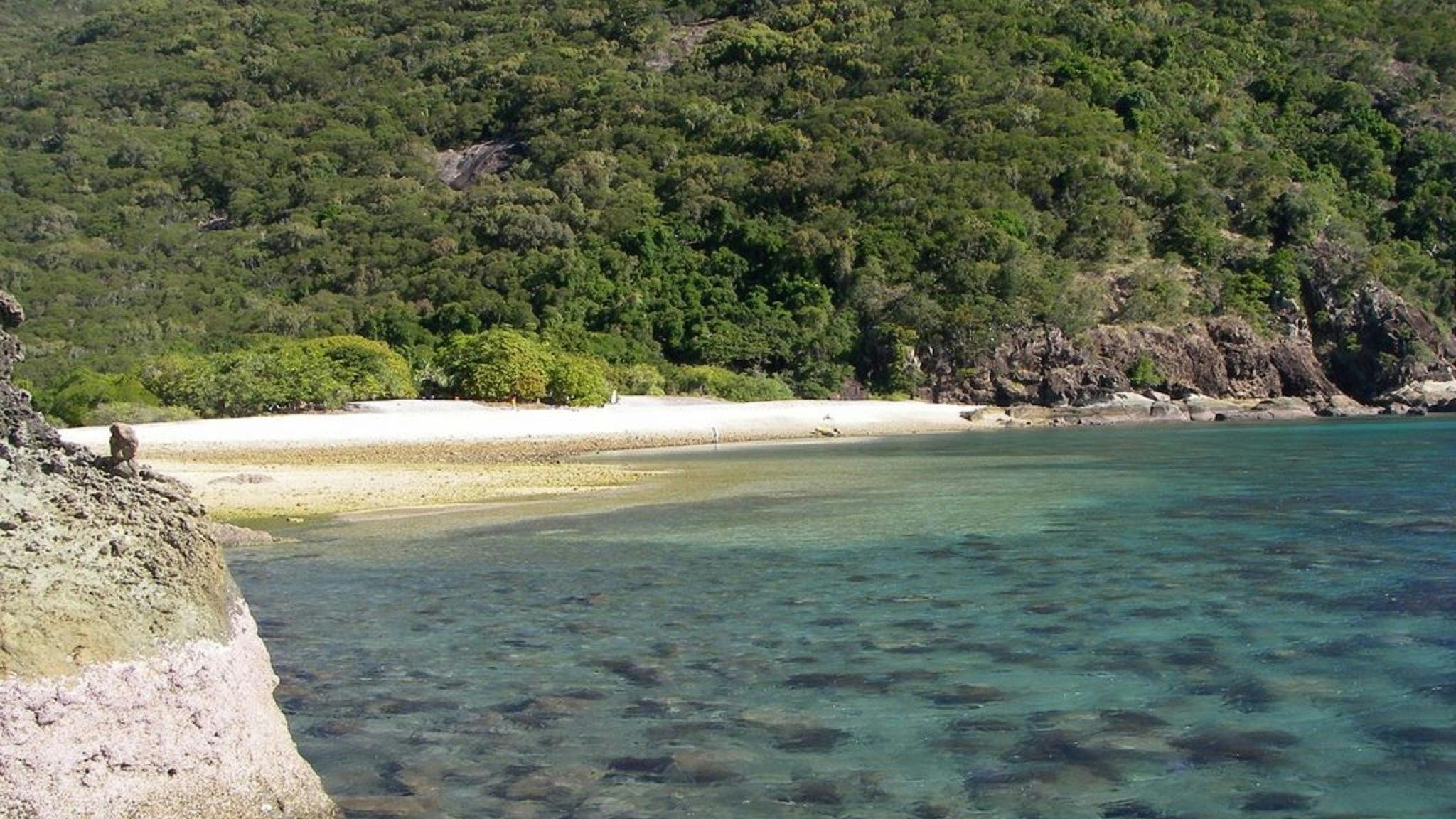 A small beach along the calm waters with rugged hills surrounding it A small beach along the calm waters with rugged hills surrounding it