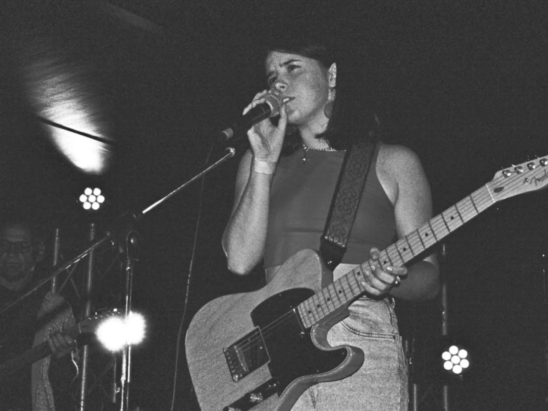 Em Davis on stage singing while holding a guitar. Black and white image.