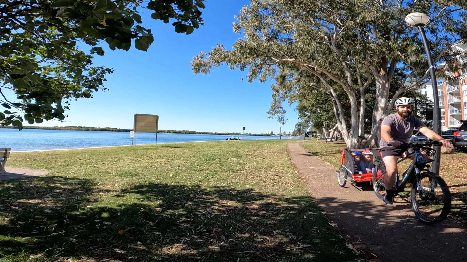 Dad taking the kids ride with a child carriage along the beauitful Maroochy River