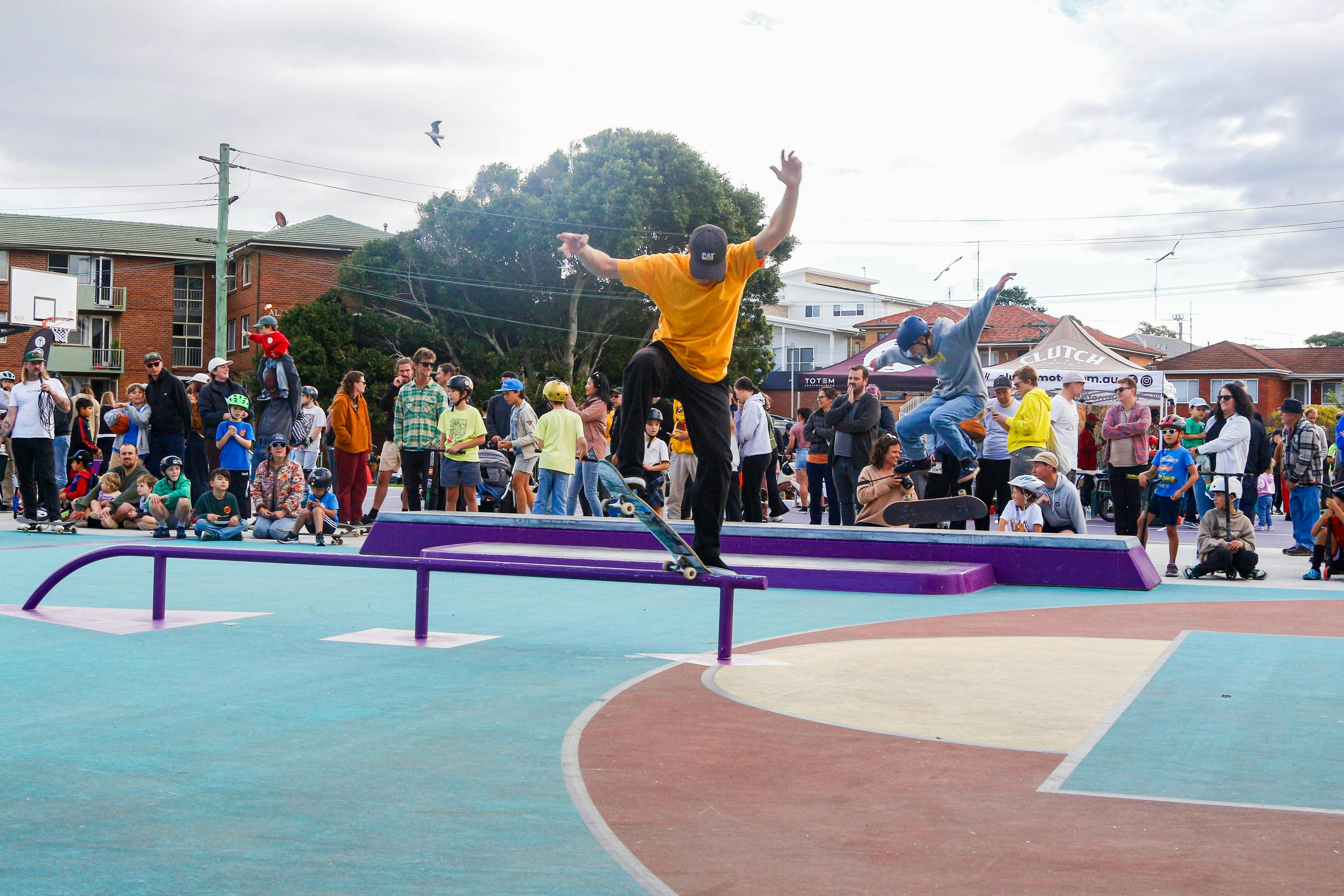 two skateboarders performing tricks before a community audience