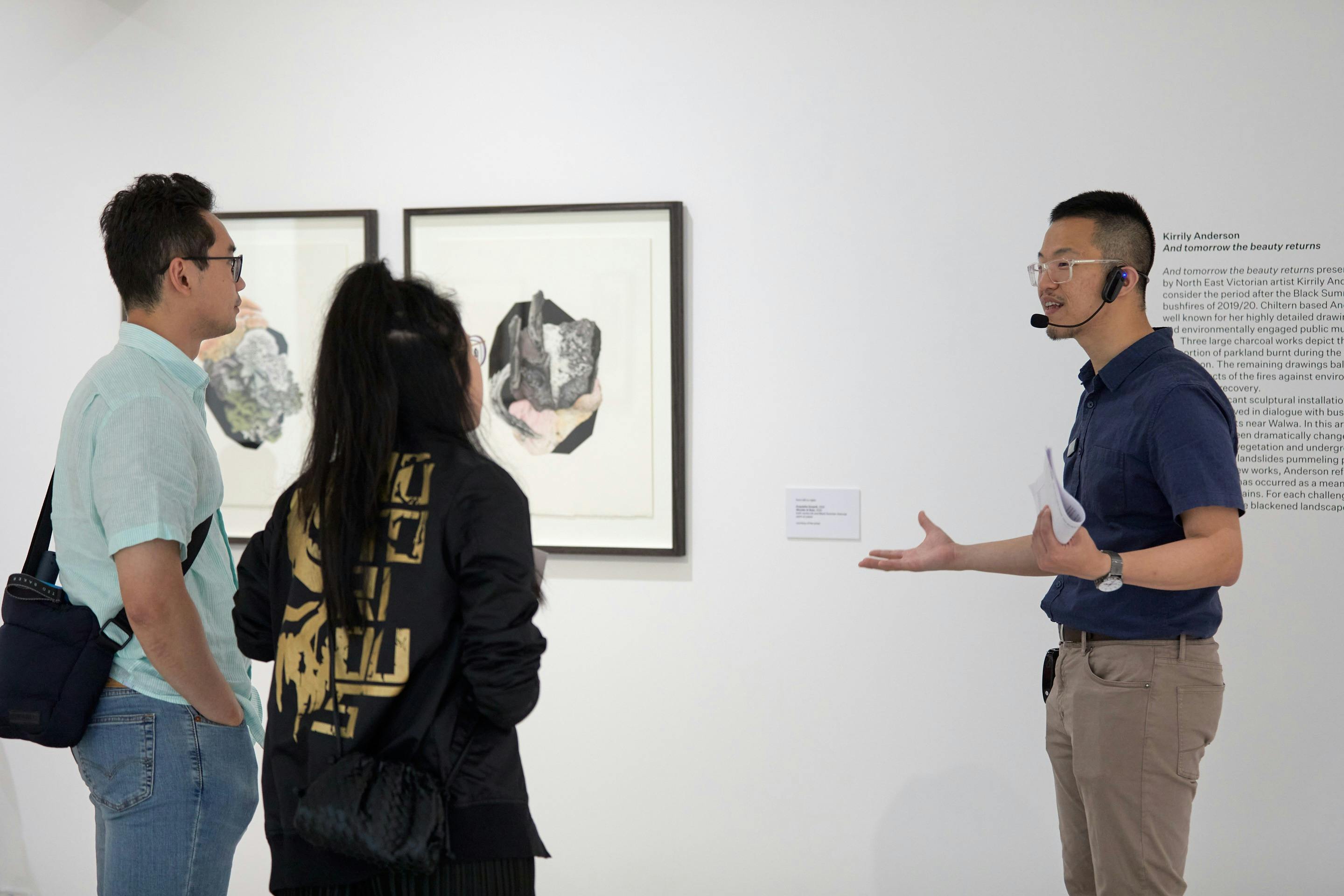 Man speaking to two visitors with a small microphone