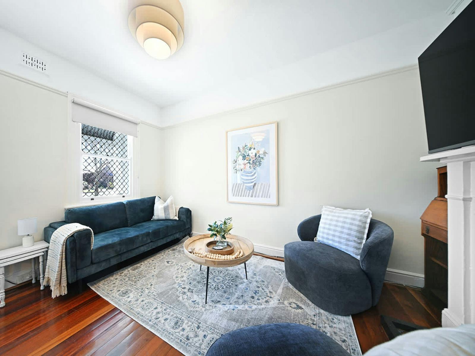 Loungeroom with a couch, 2 armchairs, a rug, a tv and a coffee table