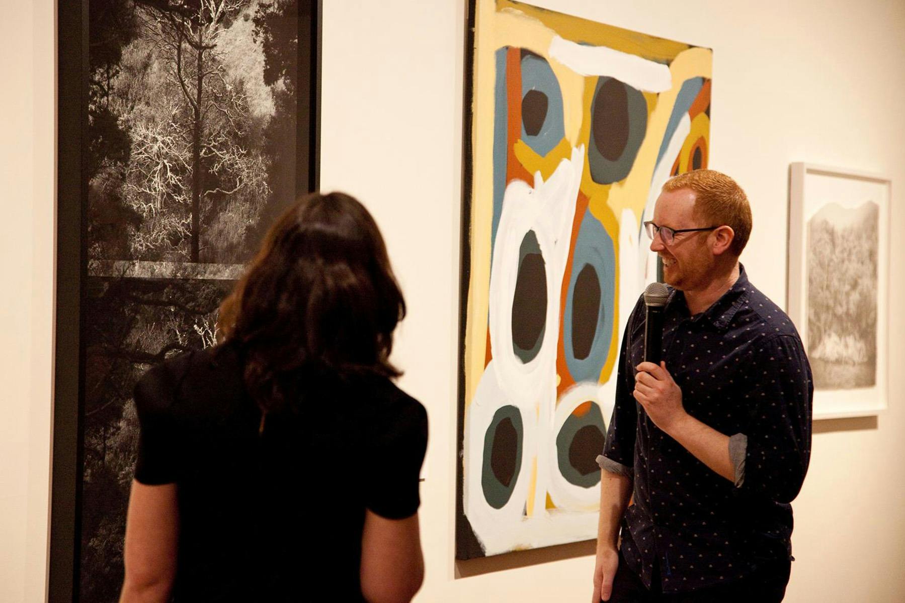 Two people look at some contemporary artwork, smiling.