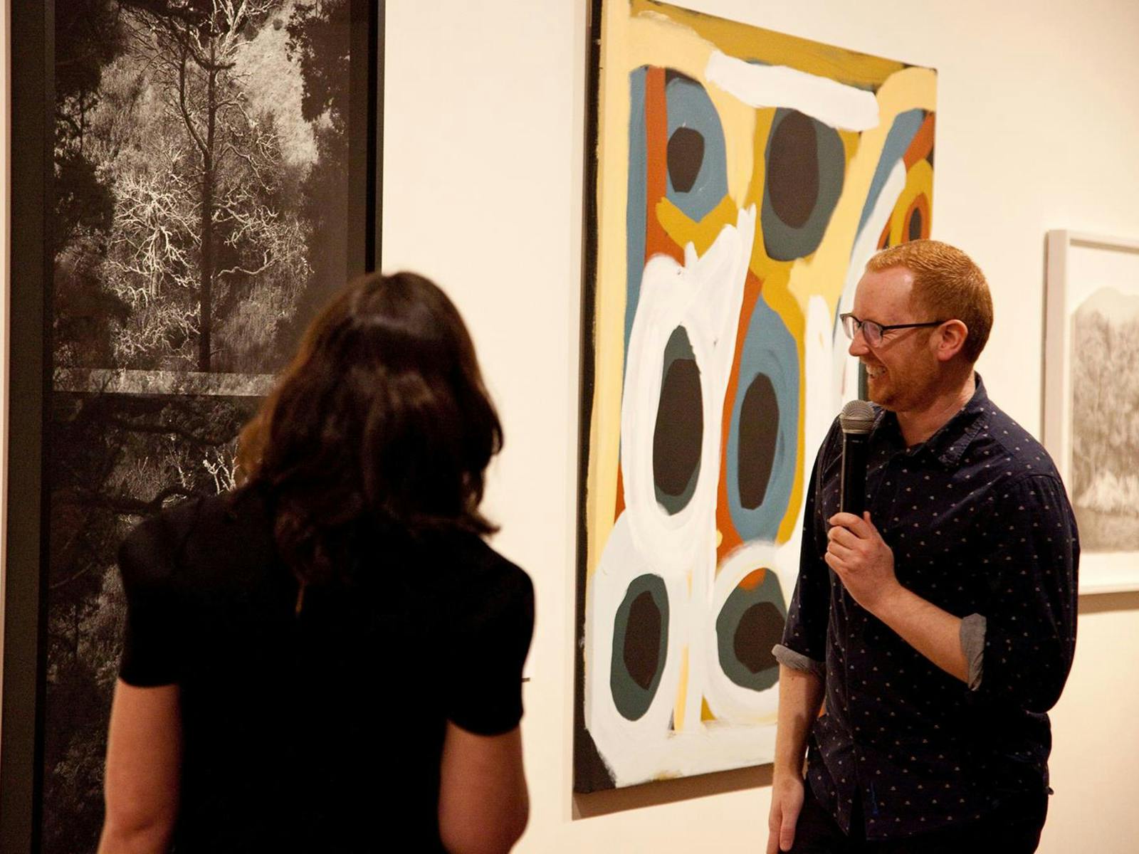Two people look at some contemporary artwork, smiling.
