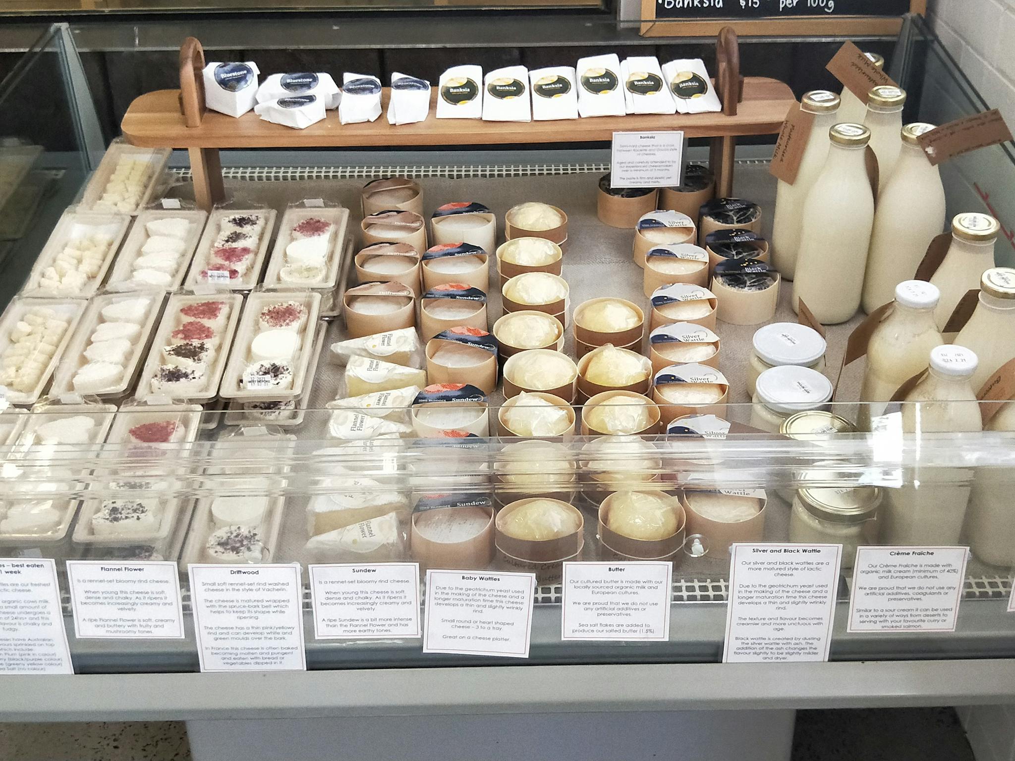 Open fridge display case with freshly made cheese, butter, creme fraiche and milk