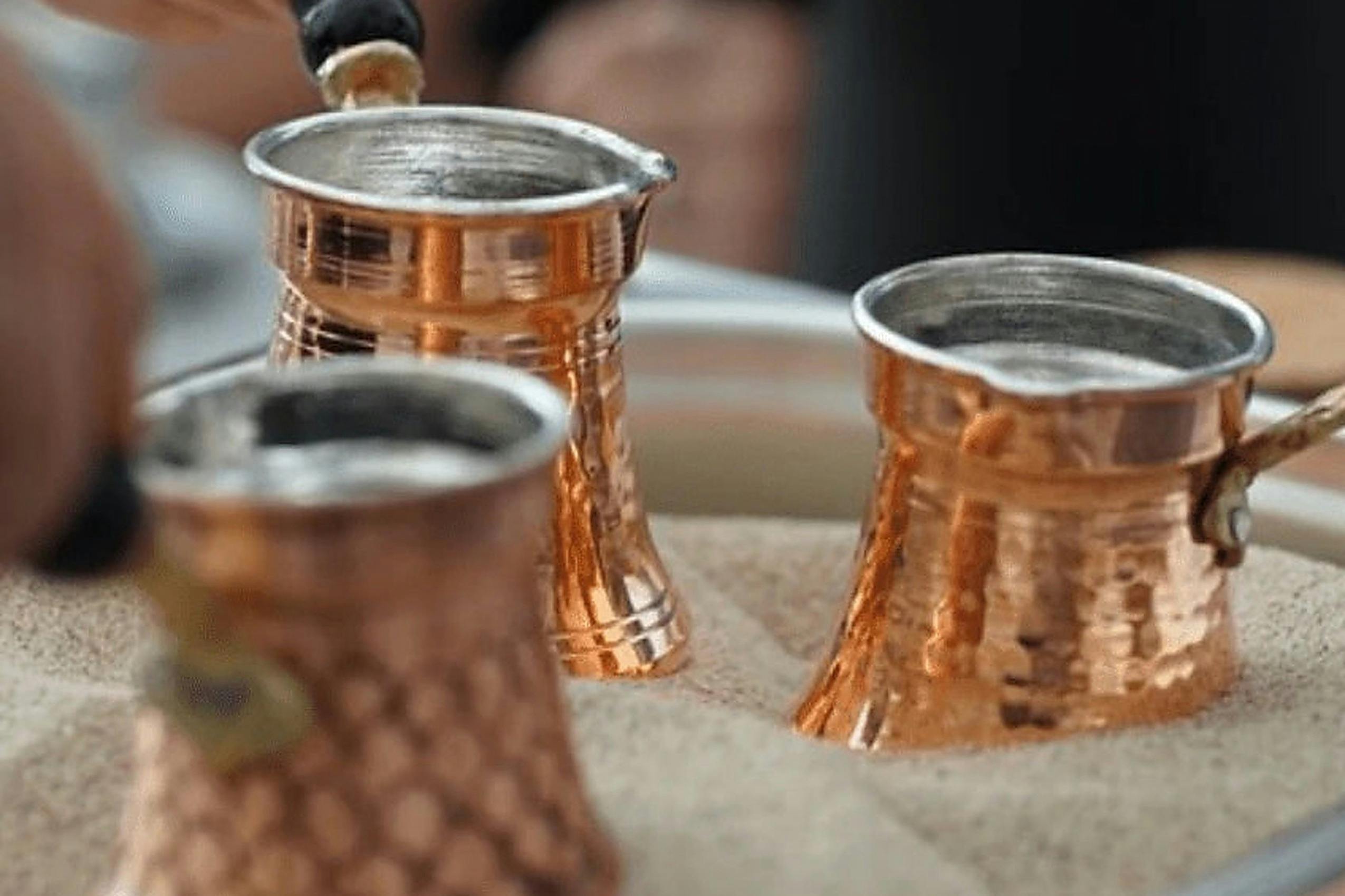 Copper cezves heating in a tray of hot sand