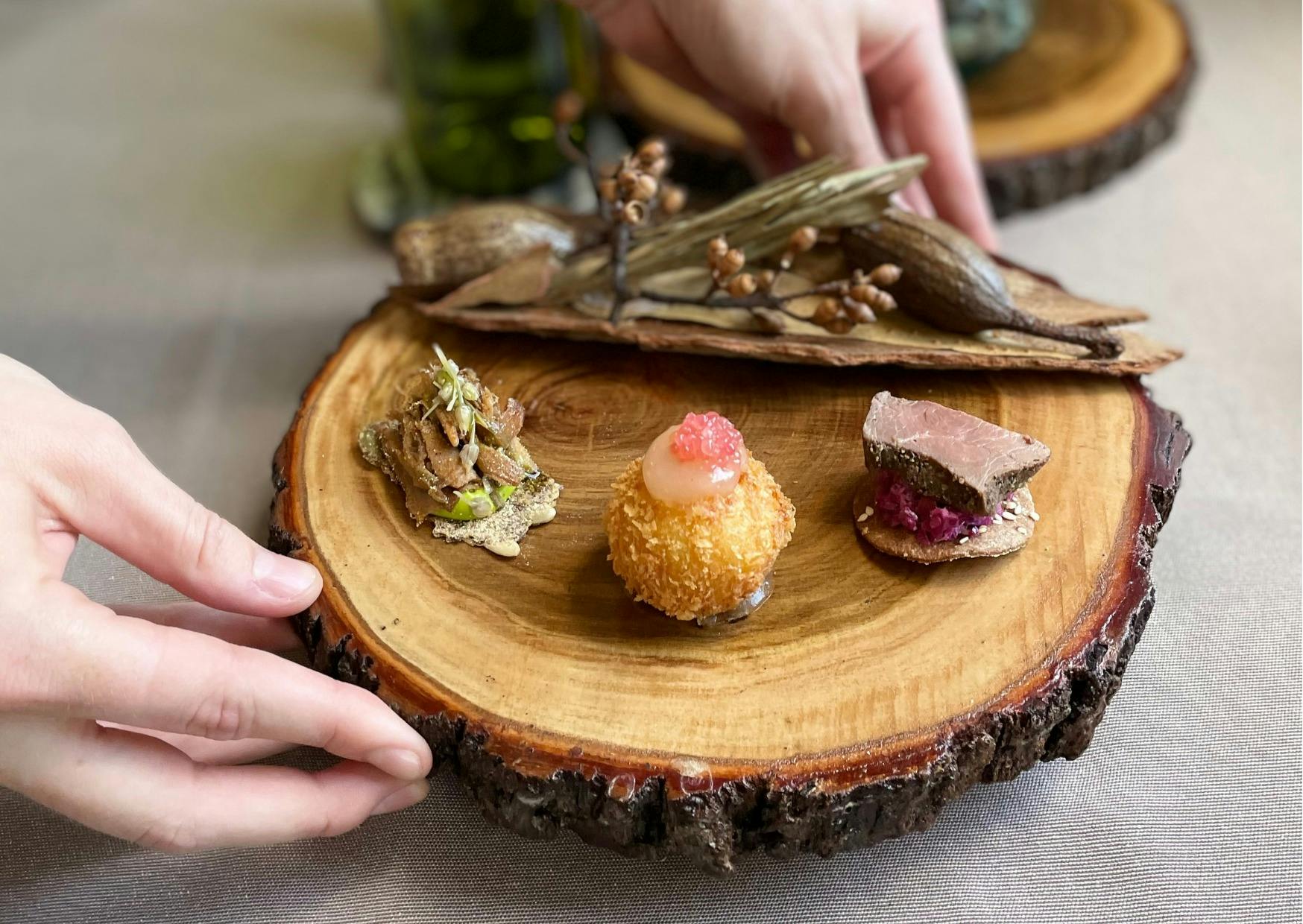 3 meticulously plated canapes rest on a polished wood round. Ruby finger lime pearls glisten.