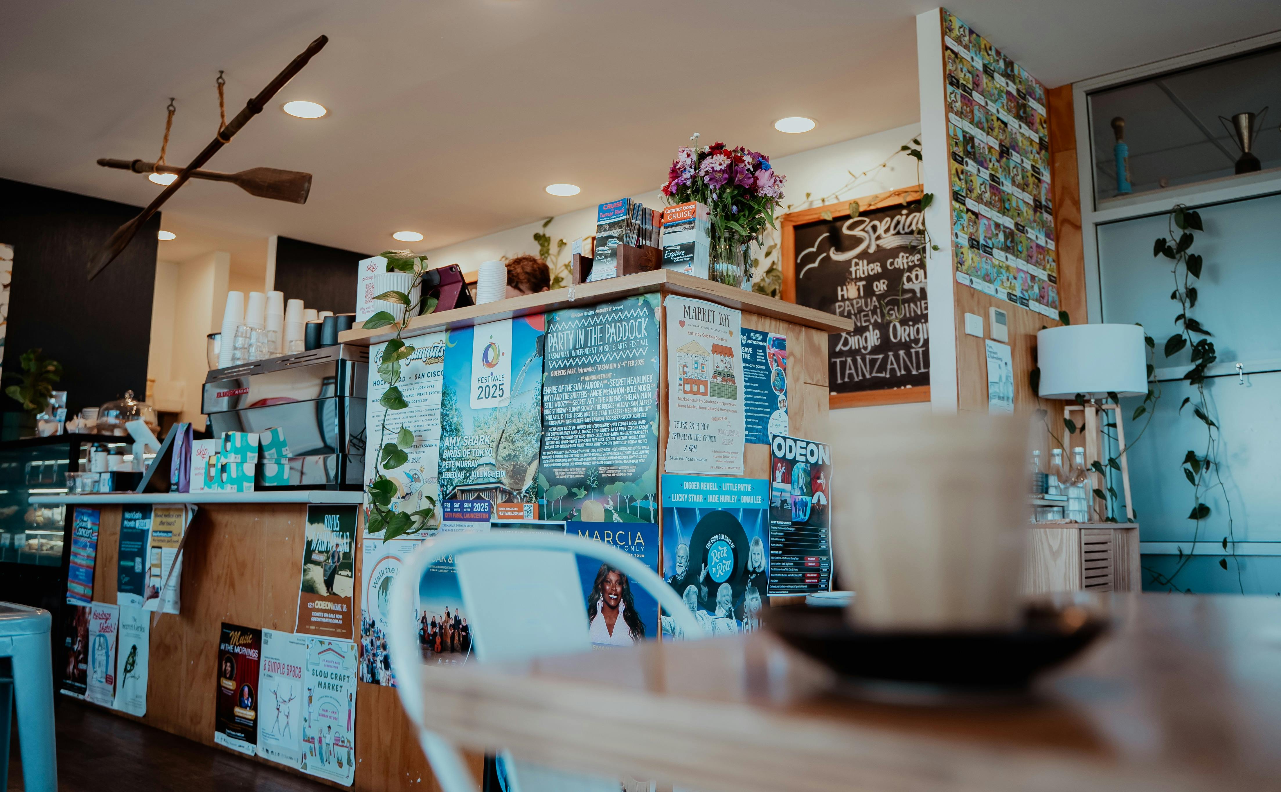A cafe serving bench with display cabinet of sweet treats and menu on the wall