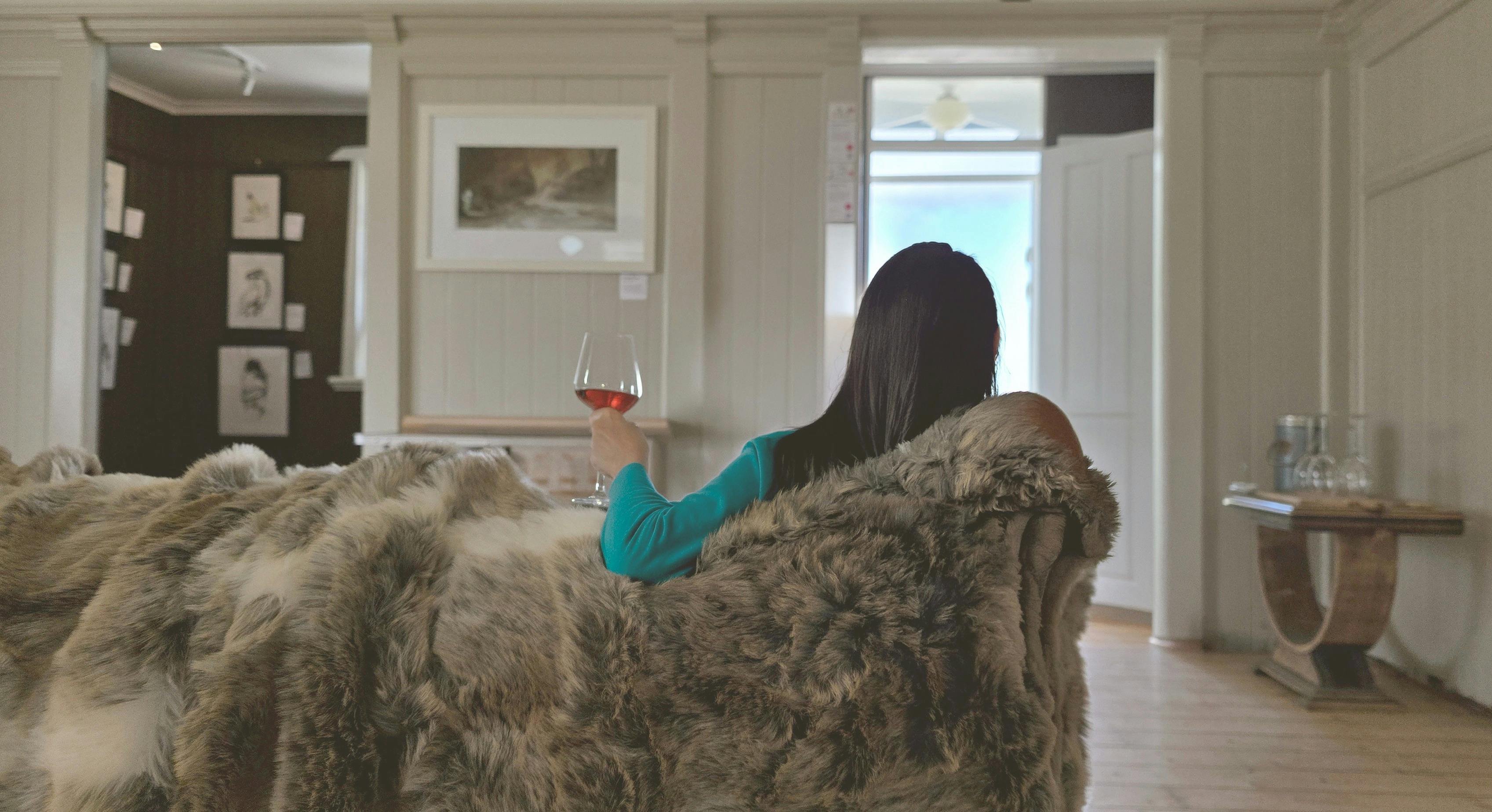 person relaxing on a lounge with a glass of wine in their hand while viewing Running Duck Studio Art