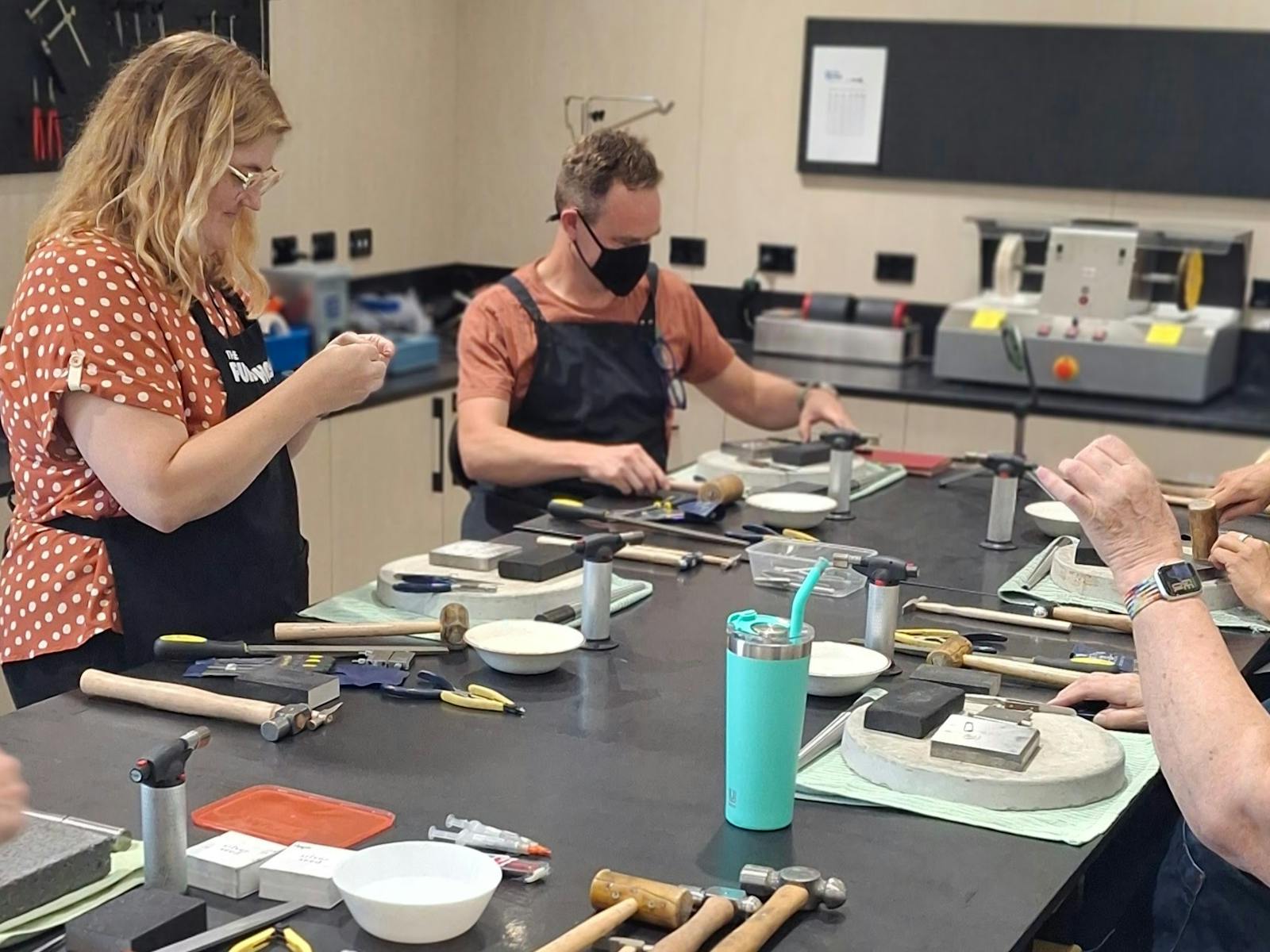 people using silversmithing tools to make jewellery