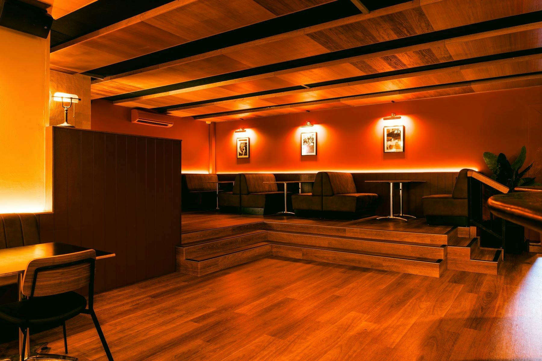 Lounge area with booths, wooden floors, and soft ambient lighting.