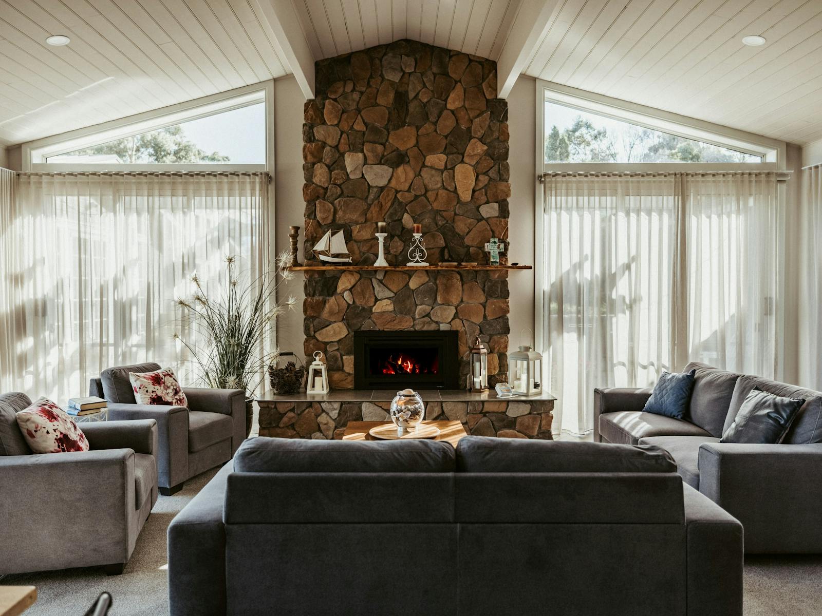 The living room offers plenty of seating, a cosy gas fireplace heater, and motorised blinds.