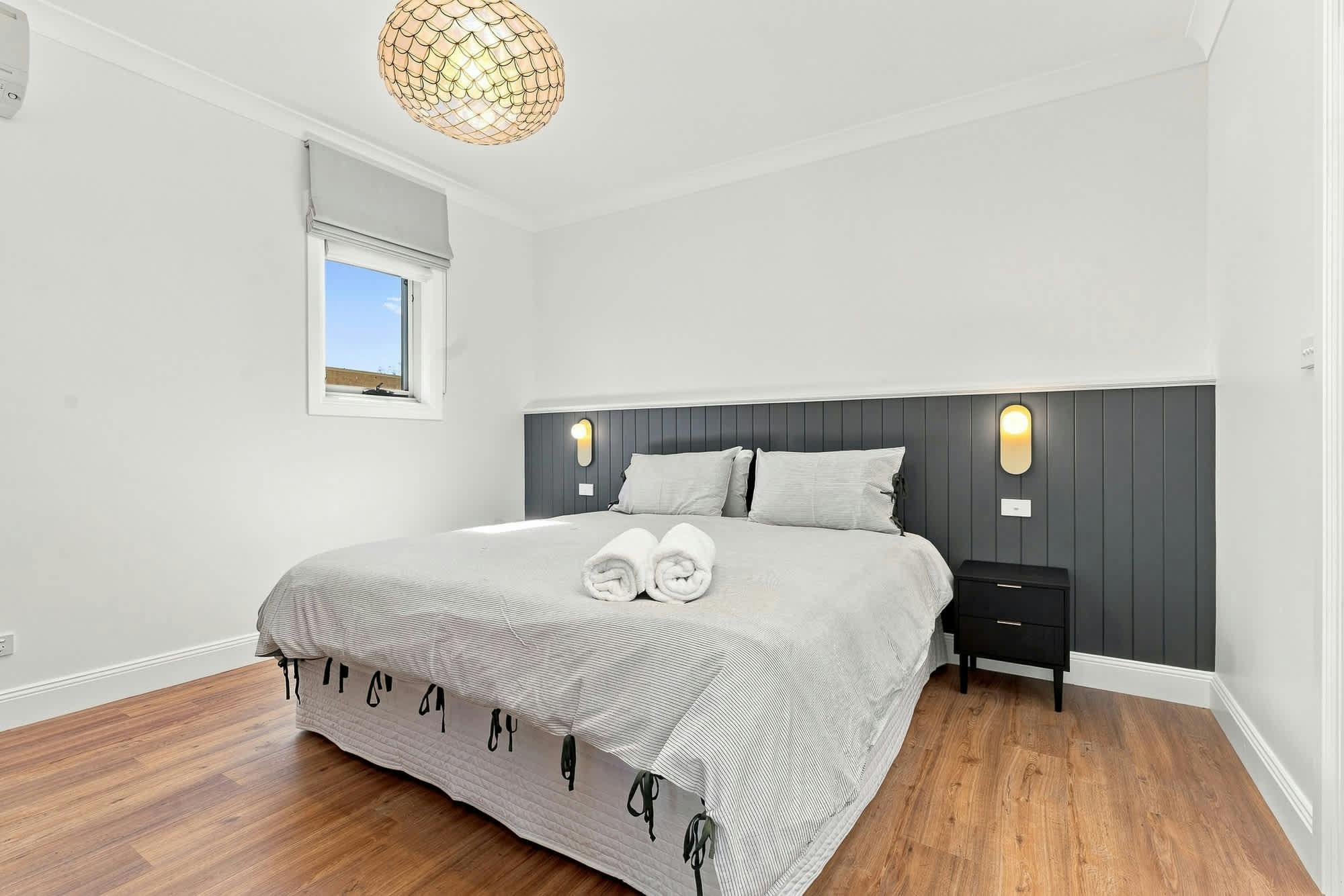 Bedroom with king bed, large window, pendant light, grey panel bed head