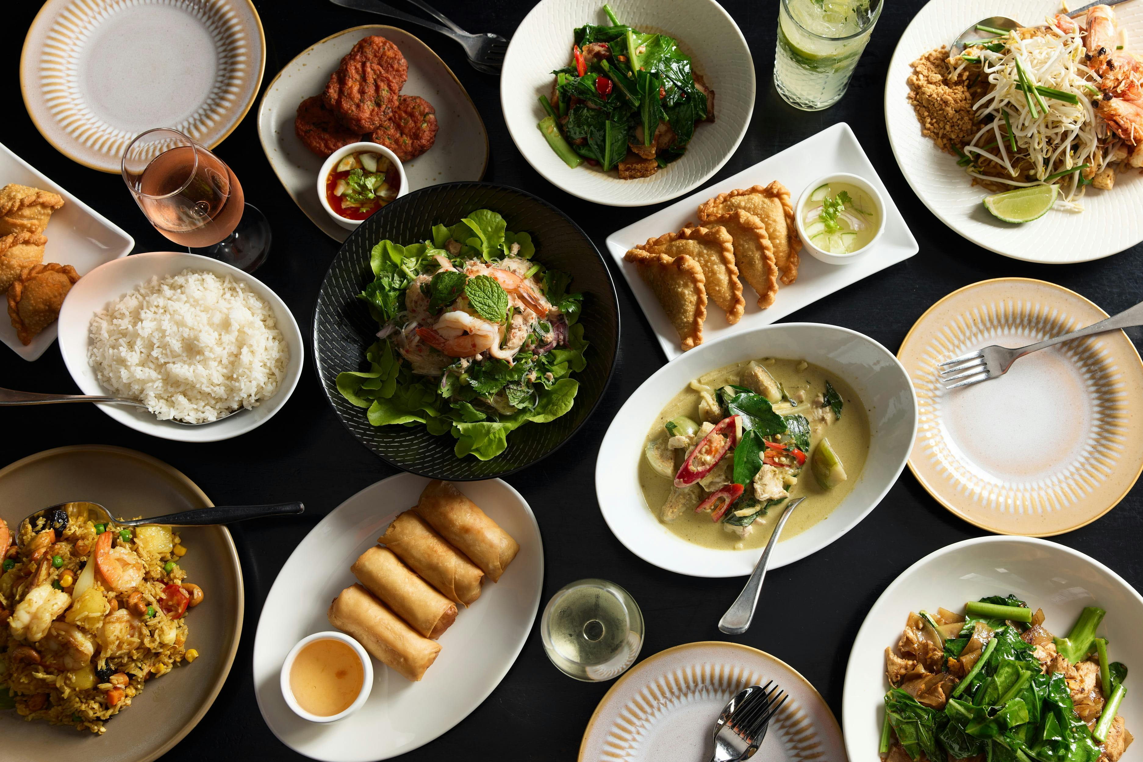 Topdown shot of a dozen Thai dishes on a table