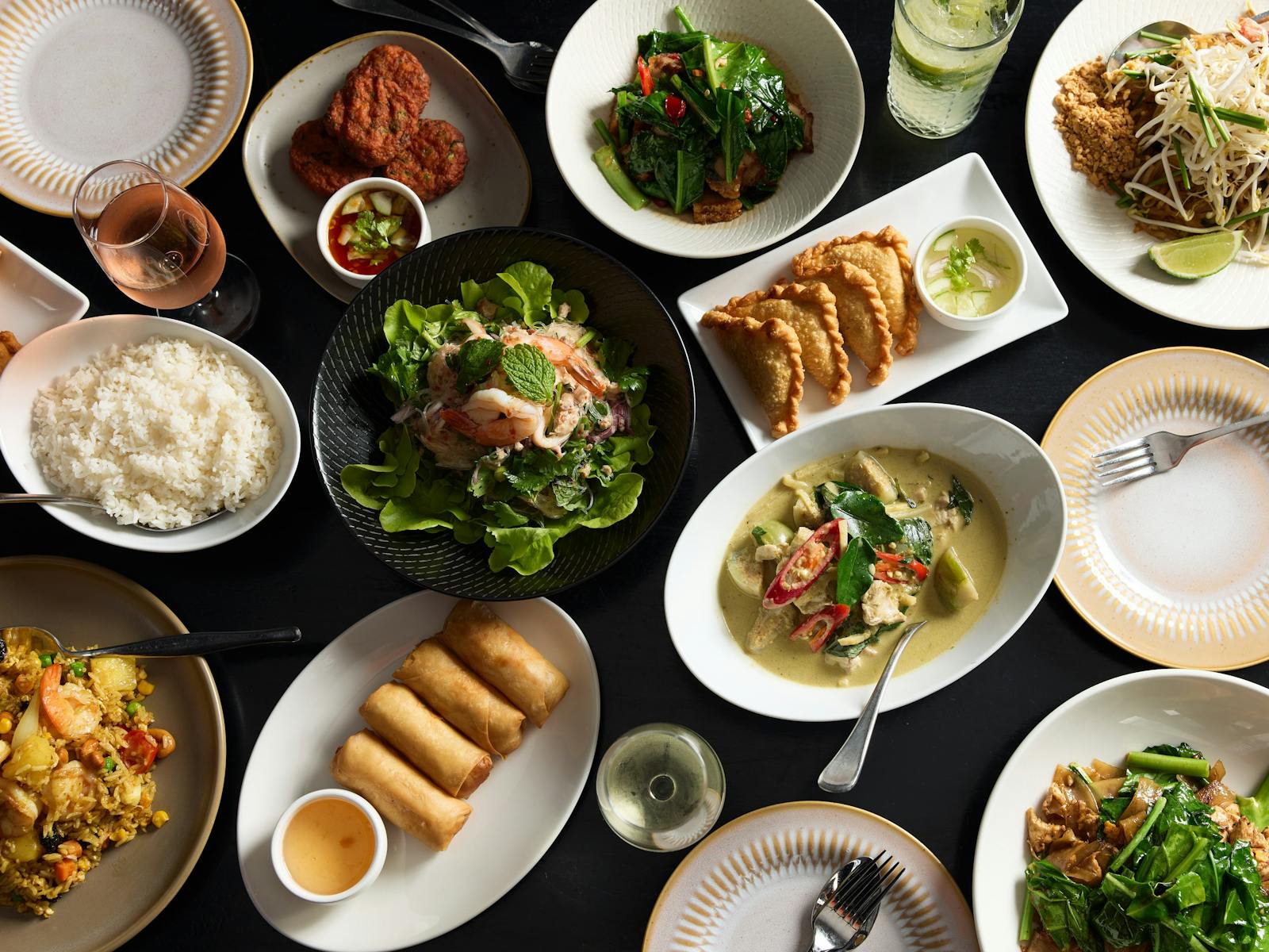 Topdown shot of a dozen Thai dishes on a table