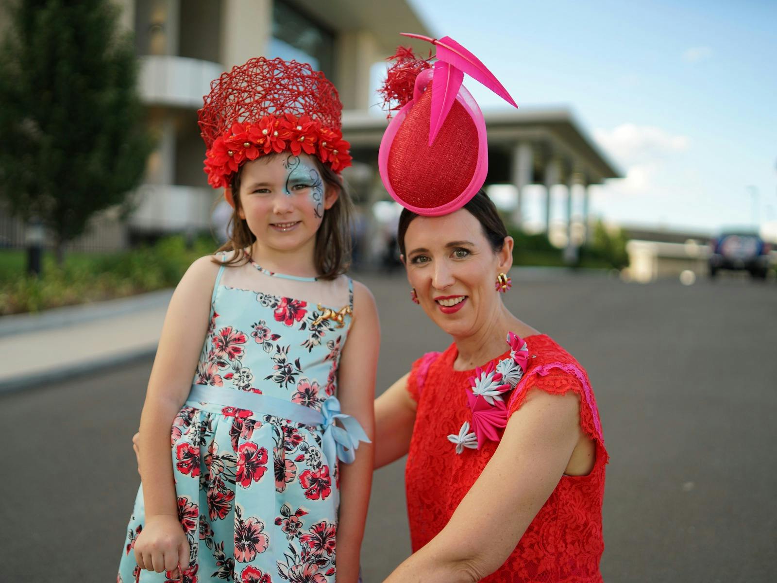 girl and woman posing for photo wearing dresses and fascinators