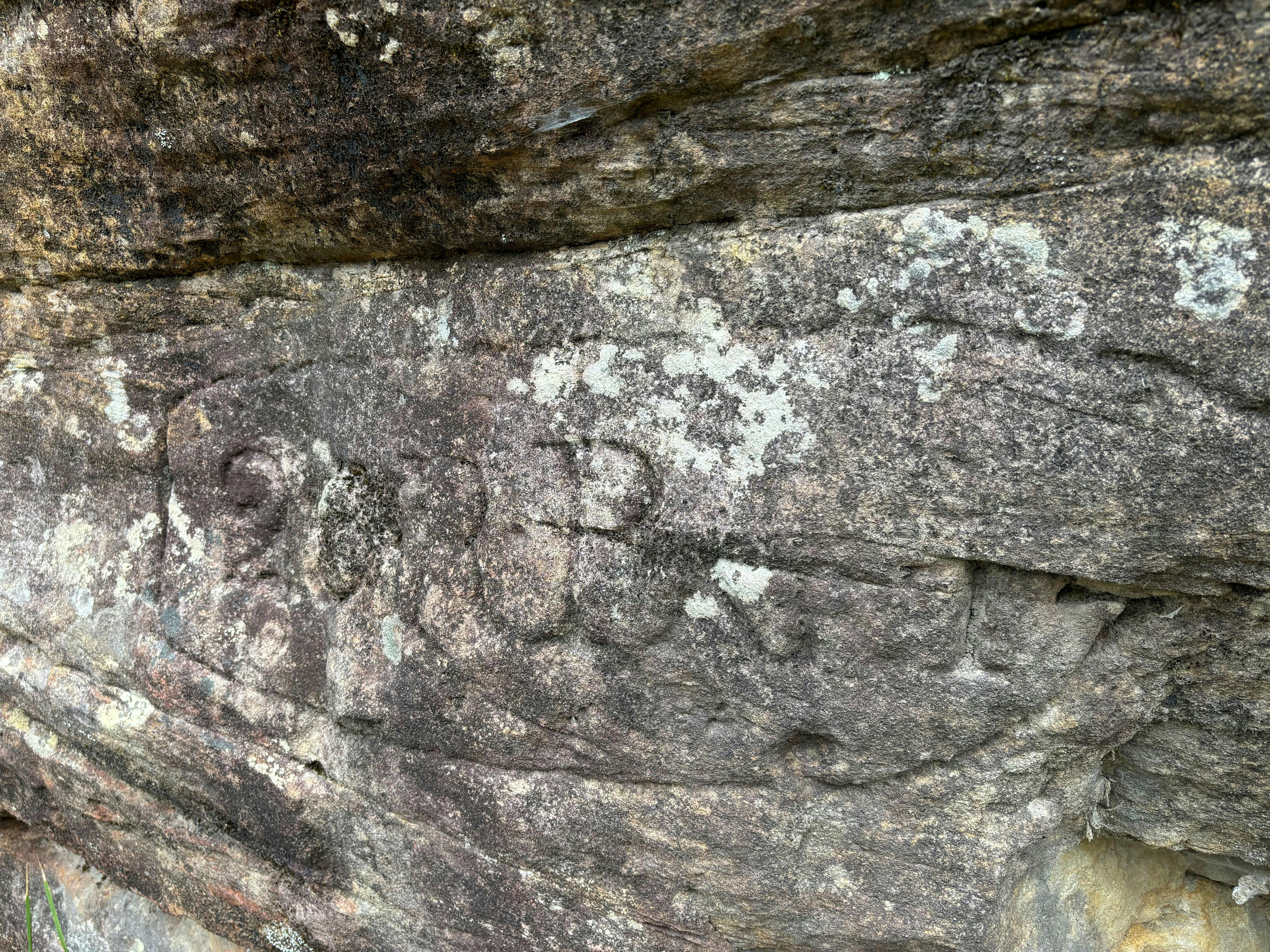 A rough sandstone rock ledge carved with letters and numbers '20 R.B'
