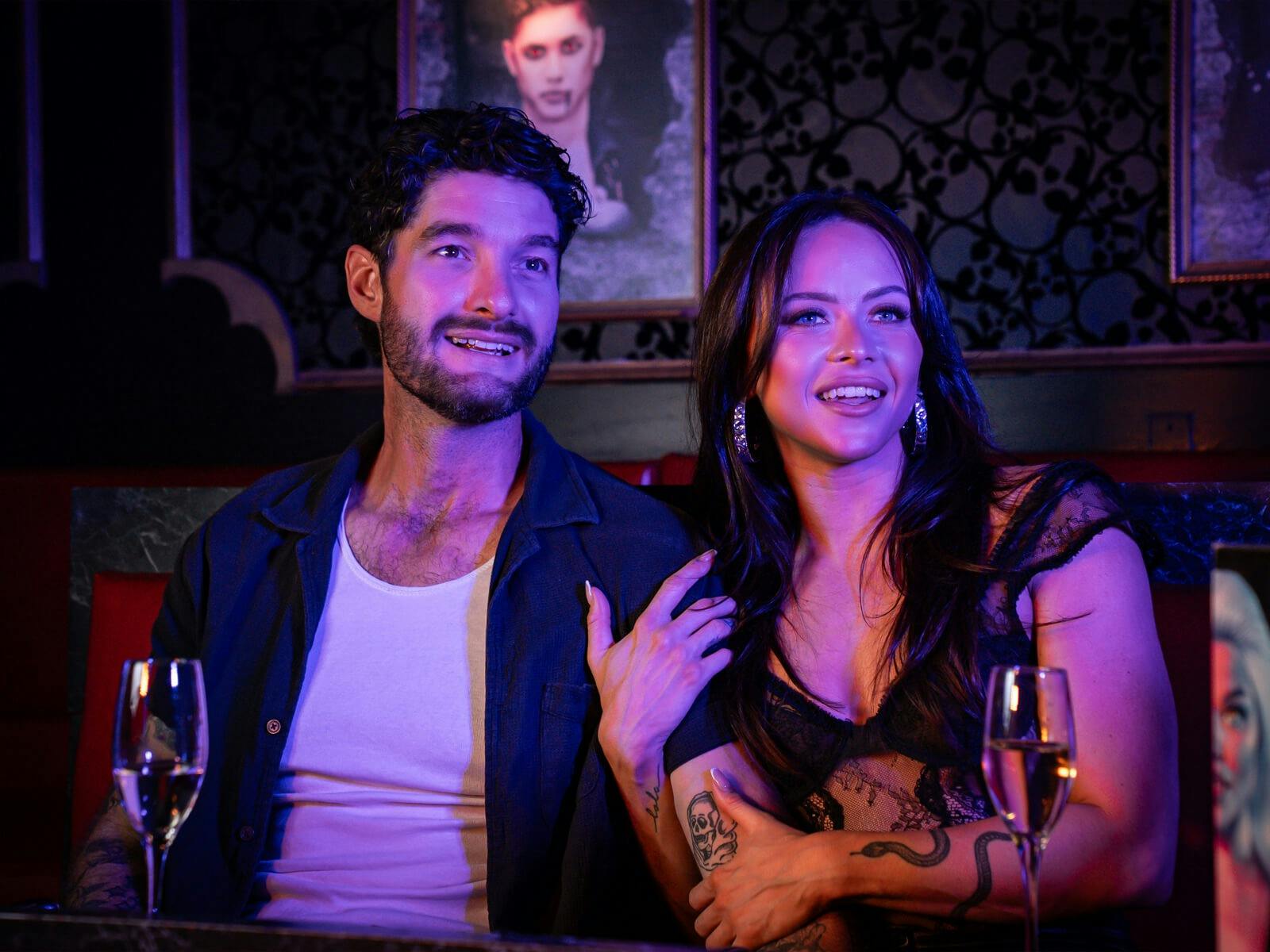 Two guests watch the show inside Dracula's, seated in a booth with sparkling wine.