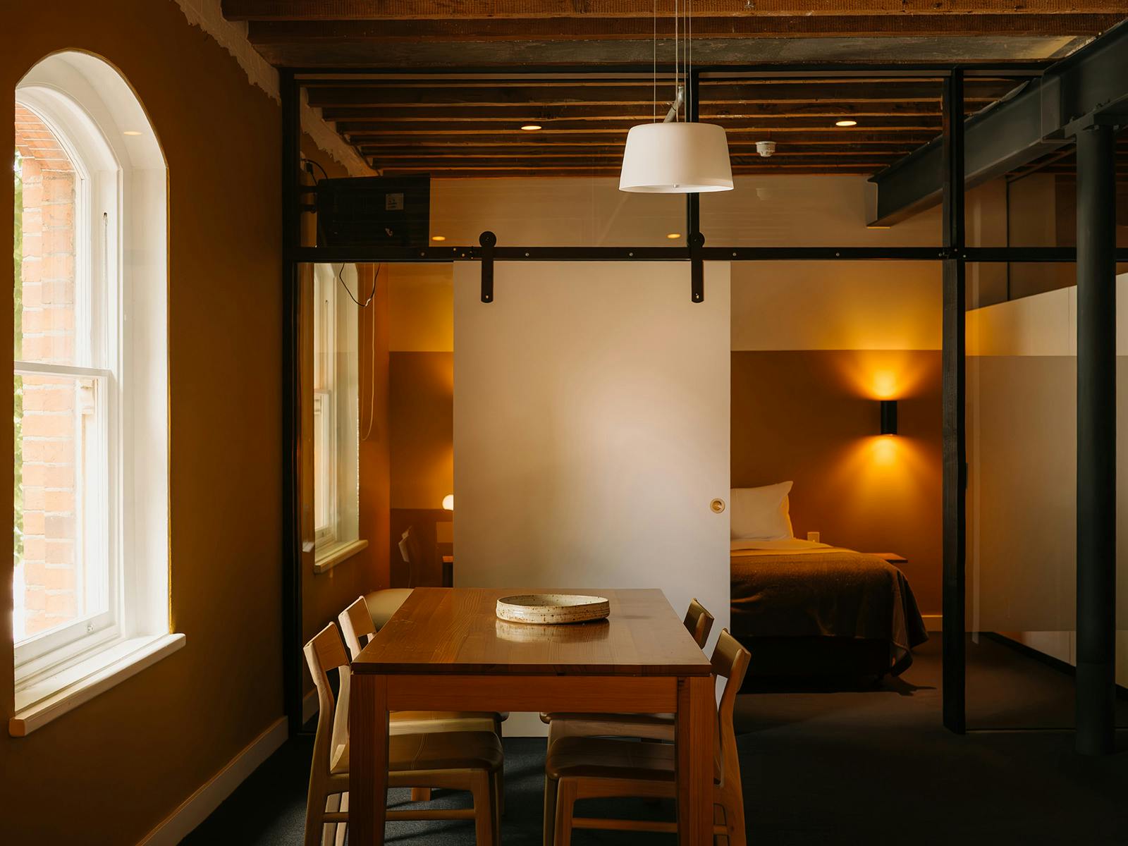 Living and dining area with arched window, timber framing, and warm lamp light.