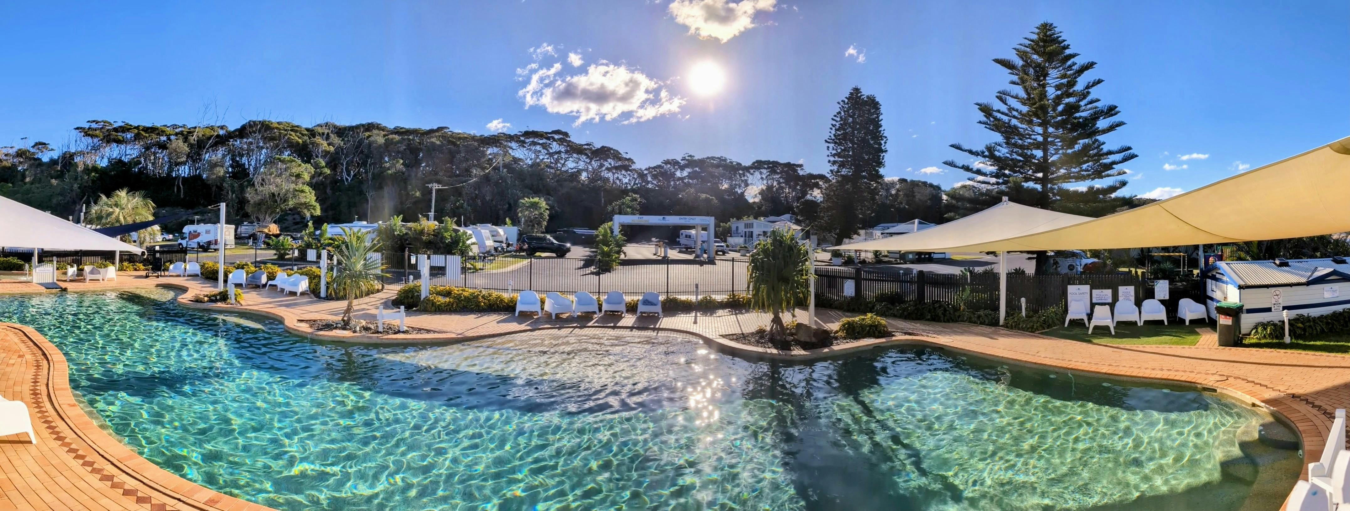 从蓝礁湖海滩度假村的泻湖式泳池拍摄的全景照片，背景中有入口。