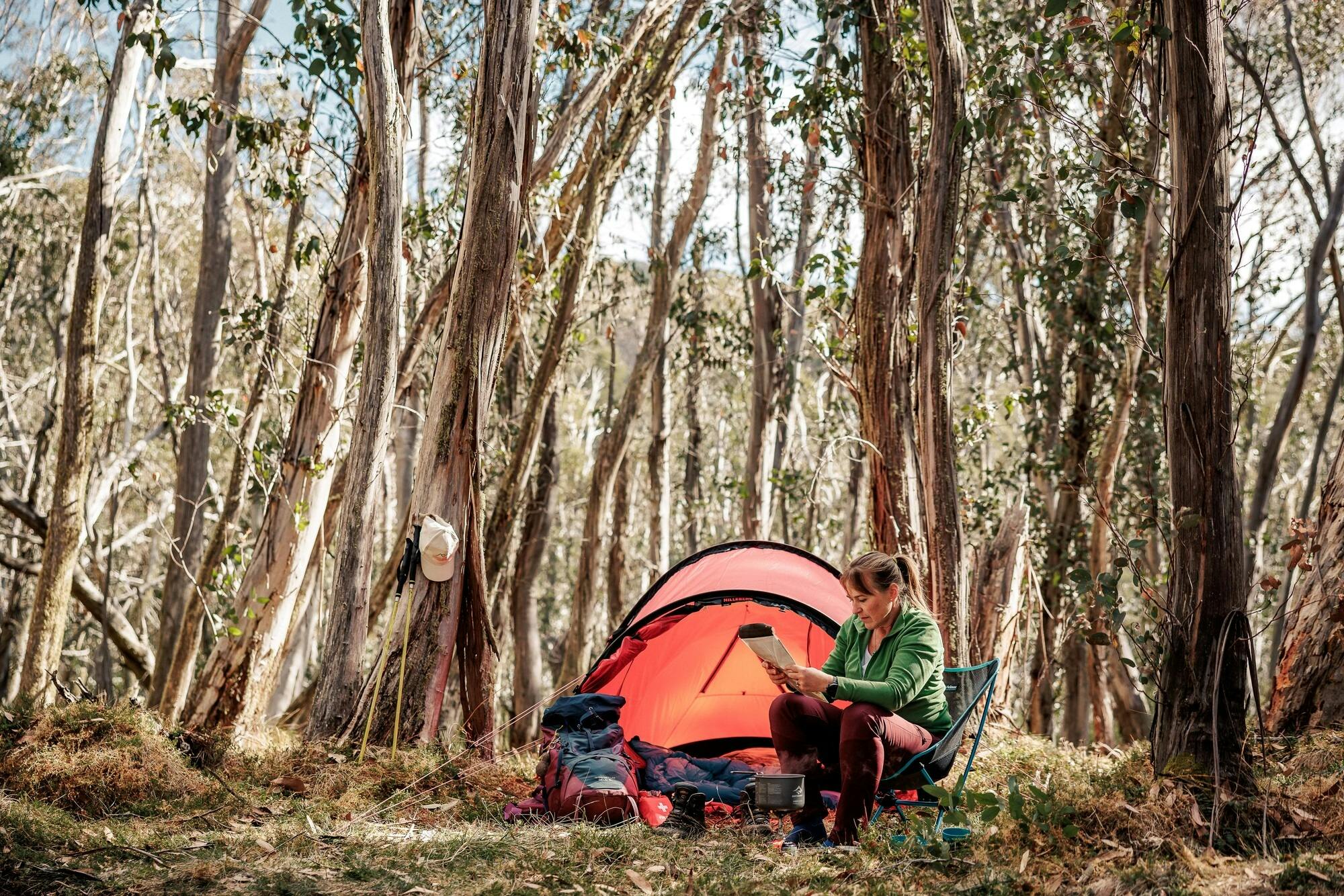 A hiker relaxing in front of her tent in a beautiful Snow Gum woodland