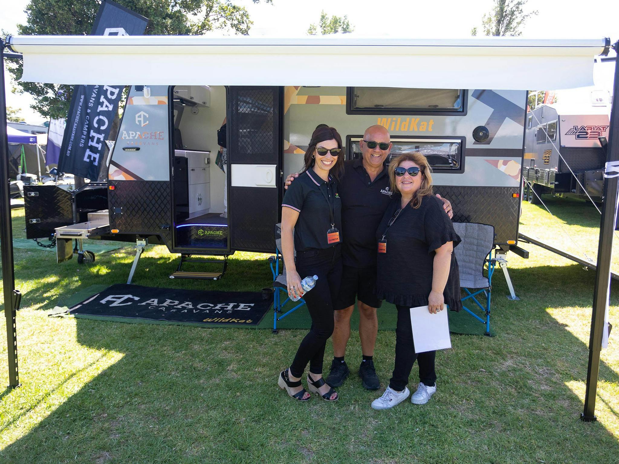 Friendly exhibitors under an awning of their caravan at the Outdoor Living & Caravan Expo