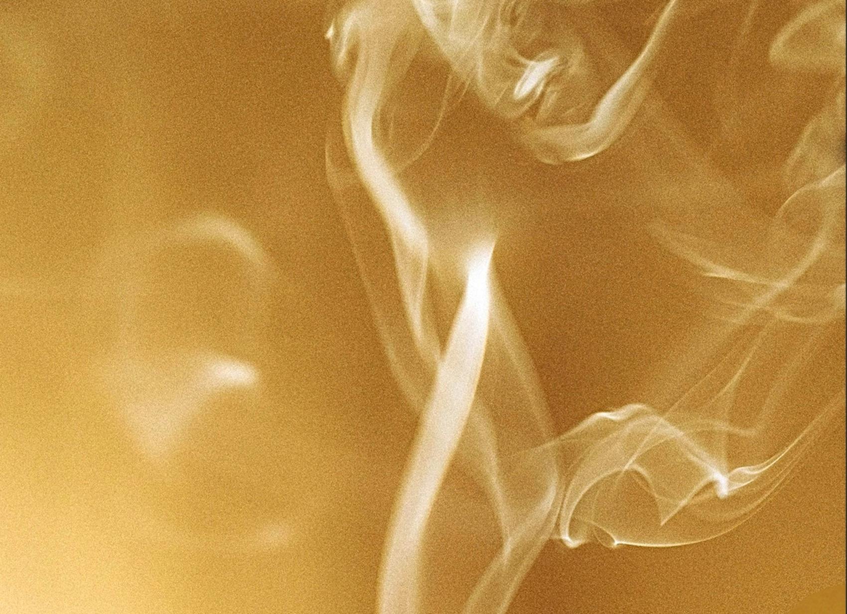 Incense smoke drifting upwards with burn orange background