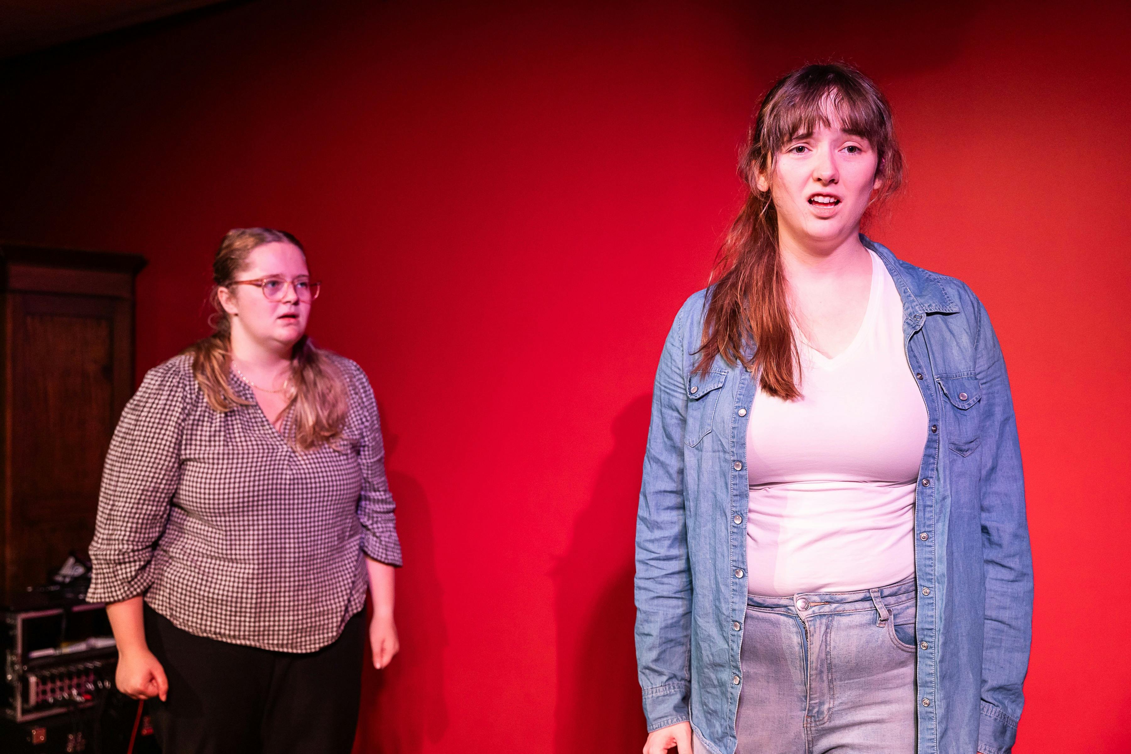 Two young women stand on stage in a moment of high emotion.