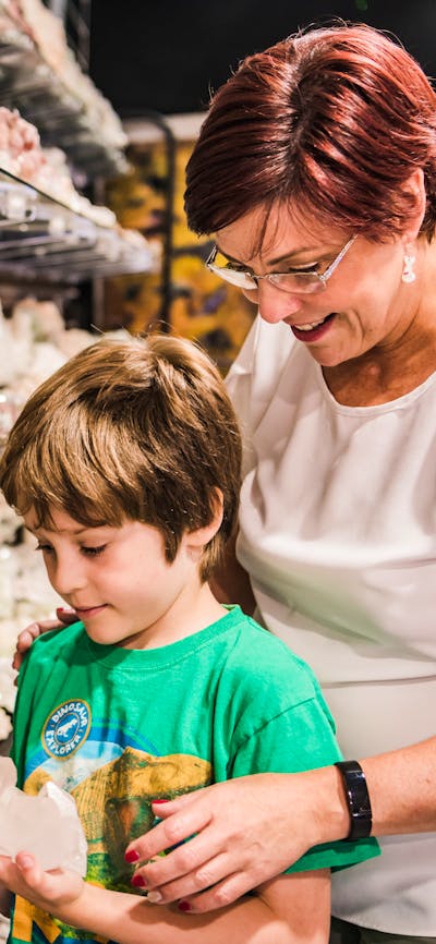 Little boy looks at clear quartz with Auntie