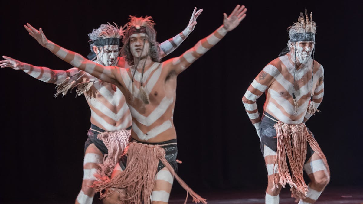 Three male First Nations dancers painted with traditional ceremonial white body paint.