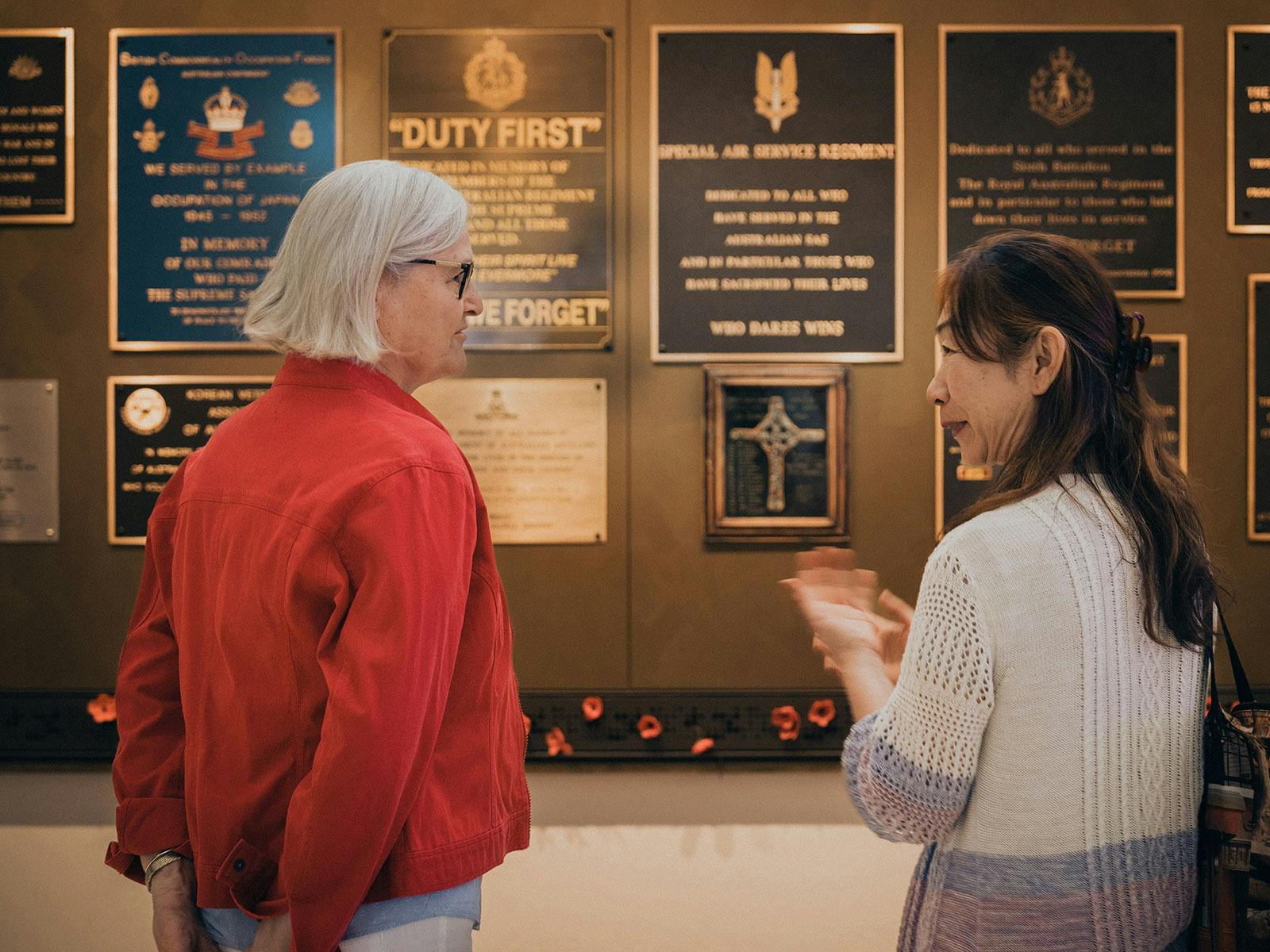 Two women discussing the plaques inside the World War II Gallery at Anzac Square