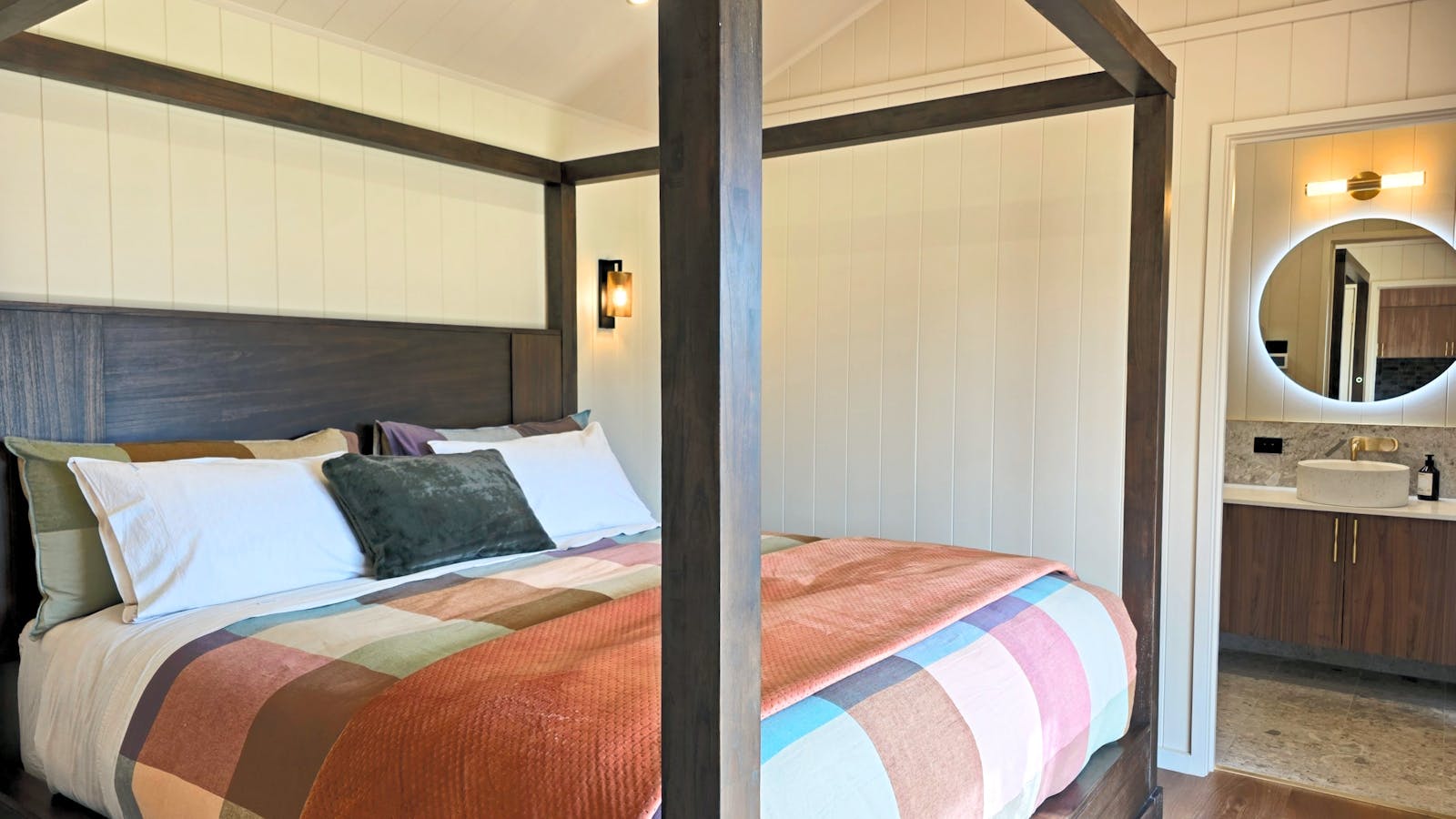 A cozy four-poster king bed, warm textures and gentle light create a calm, restful space