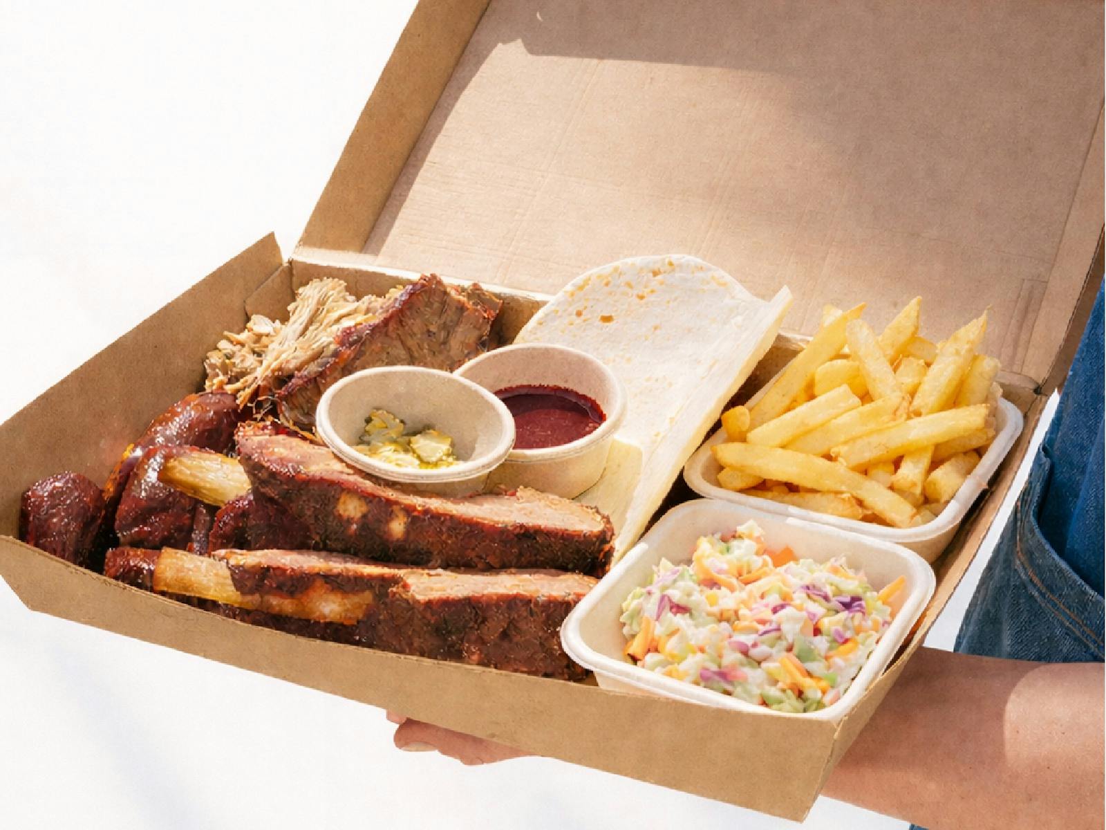 Smoked BBQ share platter with brisket, beef ribs, pulled pork, fries, coleslaw, pickles served a box Smoked BBQ share platter with brisket, beef ribs, pulled pork, fries, coleslaw, pickles served a box