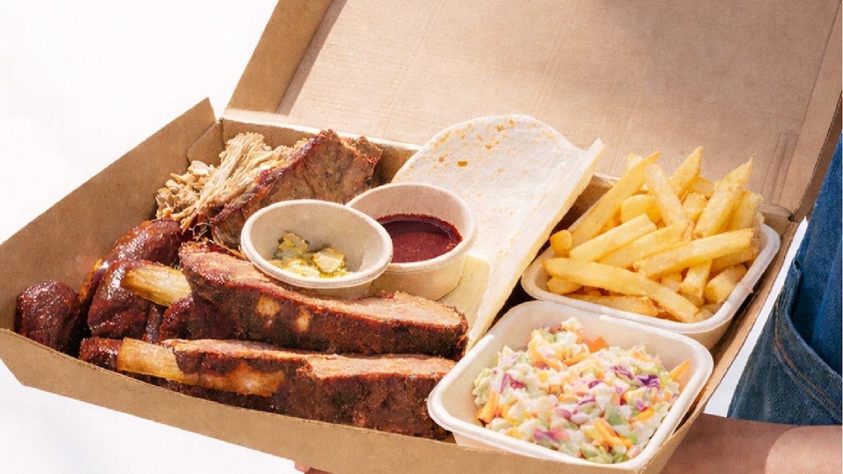 Smoked BBQ share platter with brisket, beef ribs, pulled pork, fries, coleslaw, pickles served a box