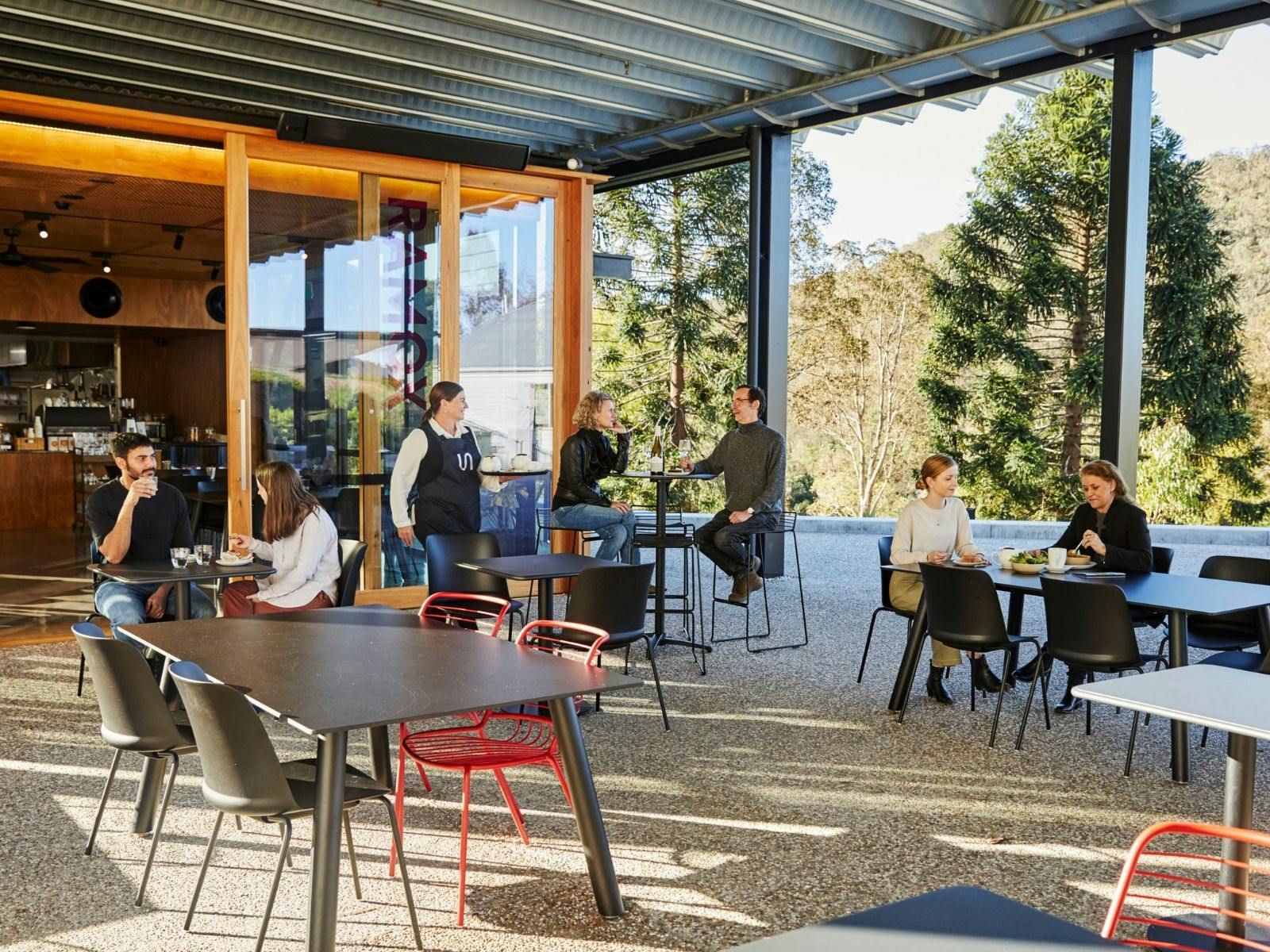 People sitting at cafe tables, eating food.
