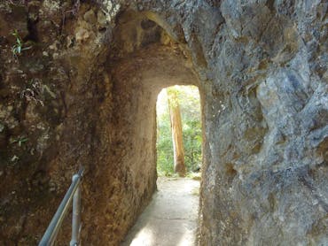 Artificial cave through rock with concrete floor and hand rail.