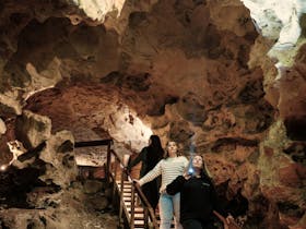 Three women stand looking up at the cave ceiling.