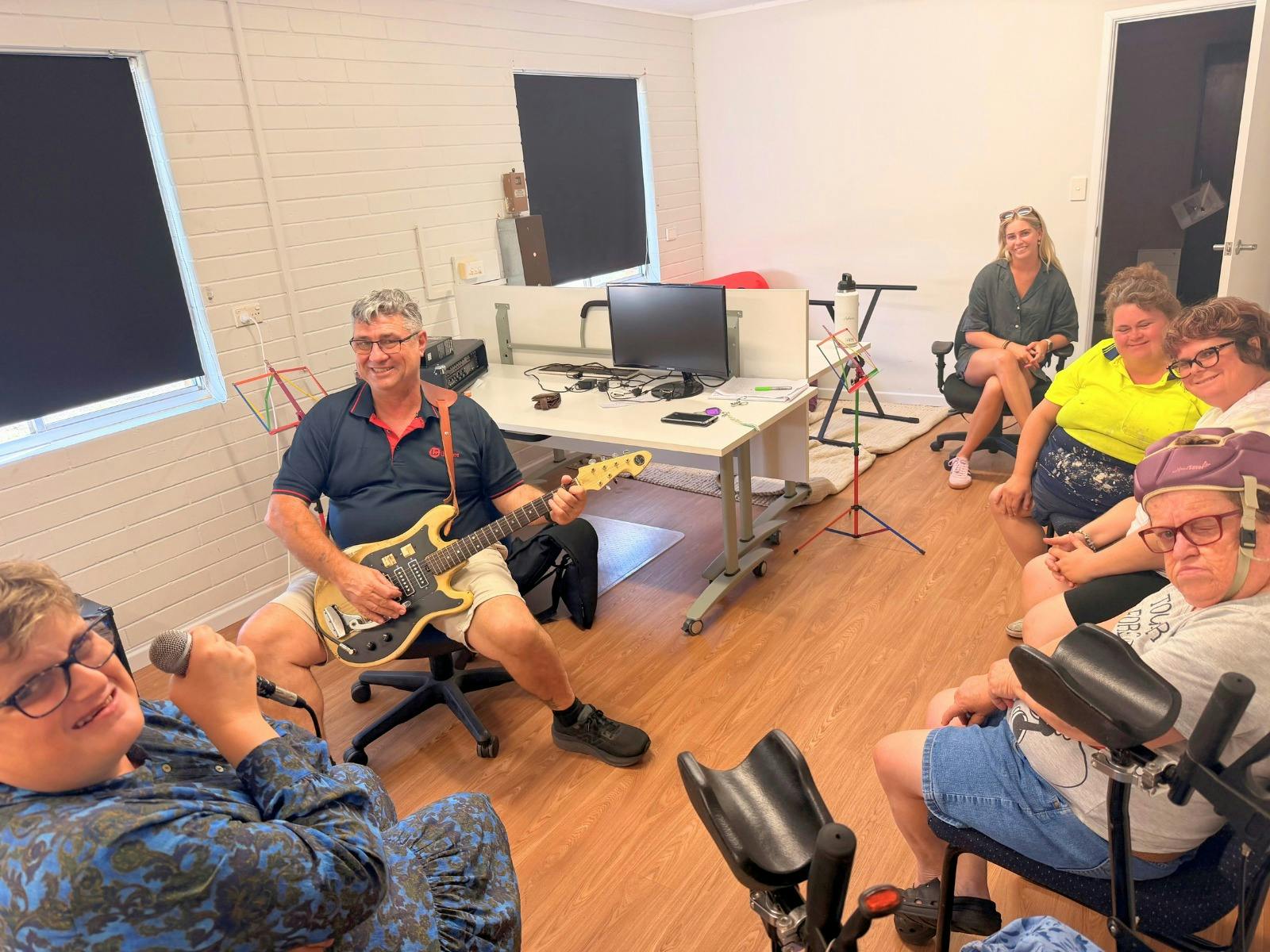 A group of musicians and singers gather in a music rehearsal room at Caringa.