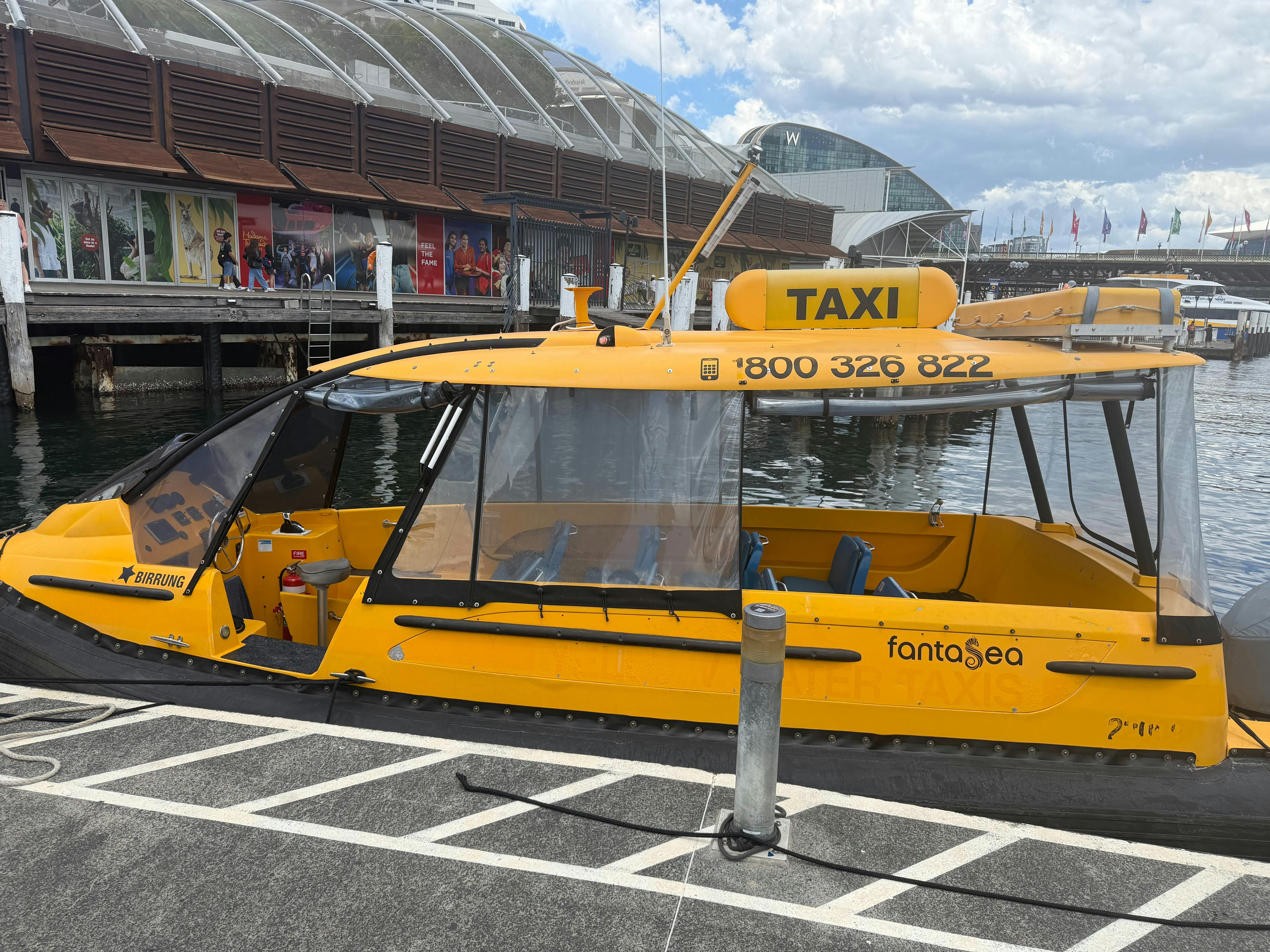 A Sydney Harbour Water Taxis vessel crossing the harbour with the Sydney Opera House behind it.