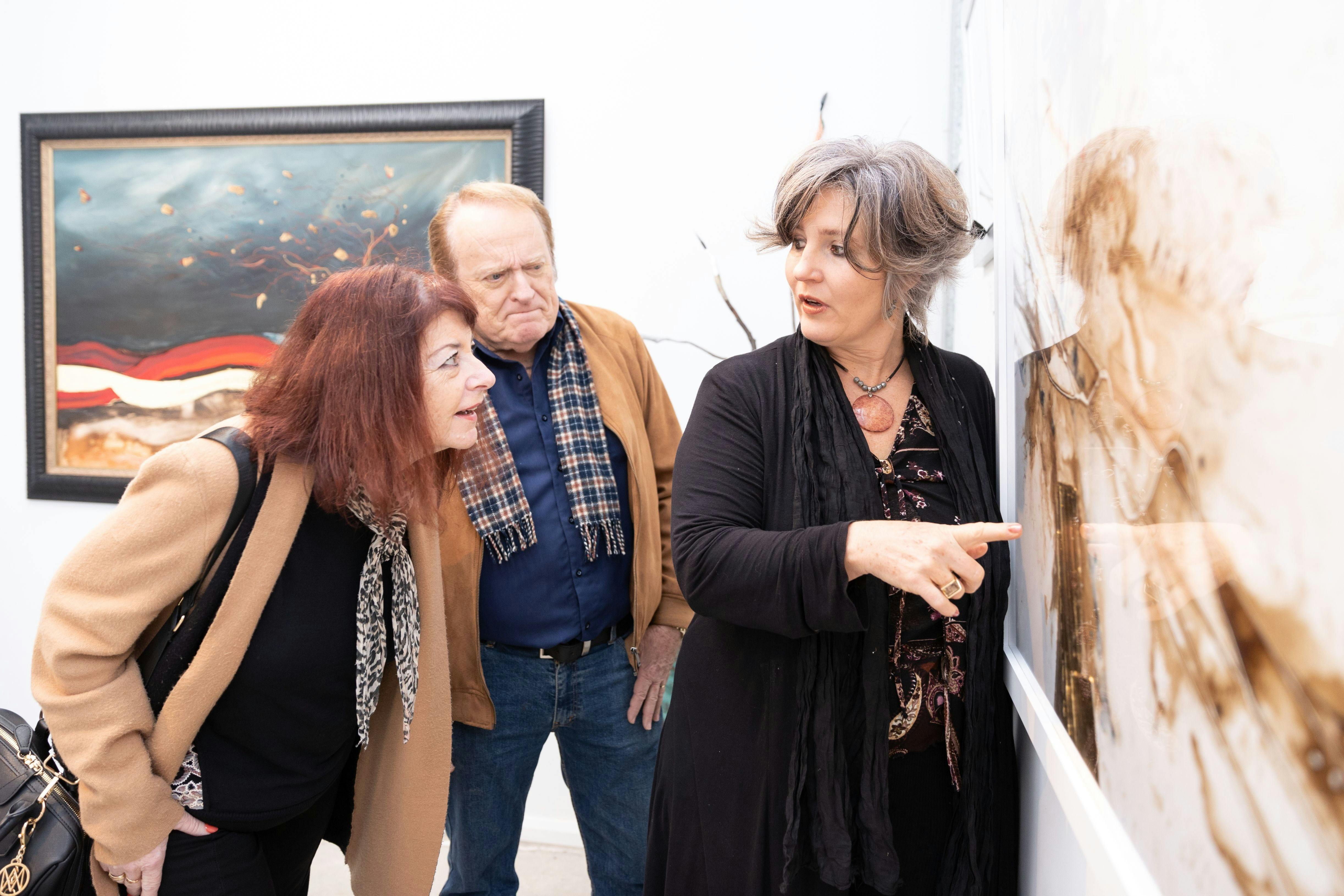 Artist Christa Coetzee explaining her artwork hanging in her private studio
