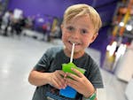 A little boy enjoys a green and blue slushie