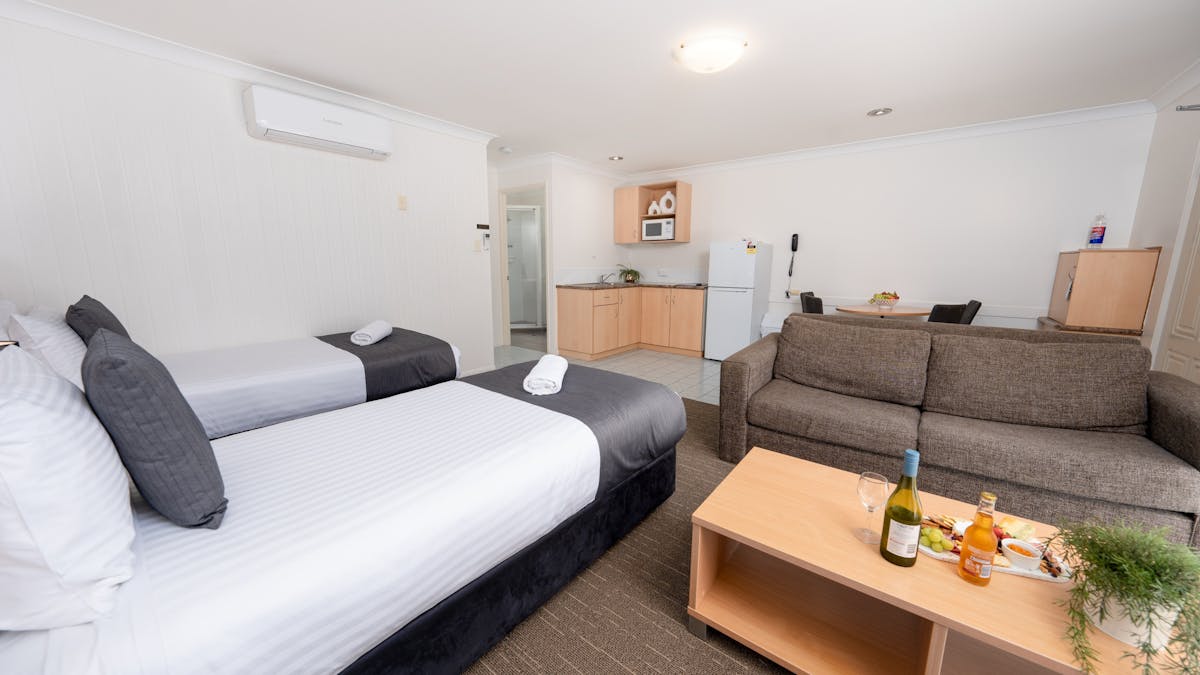 Family Suite with Queen Bed and two Single Beds, open plan living with lounge area and kitchenette