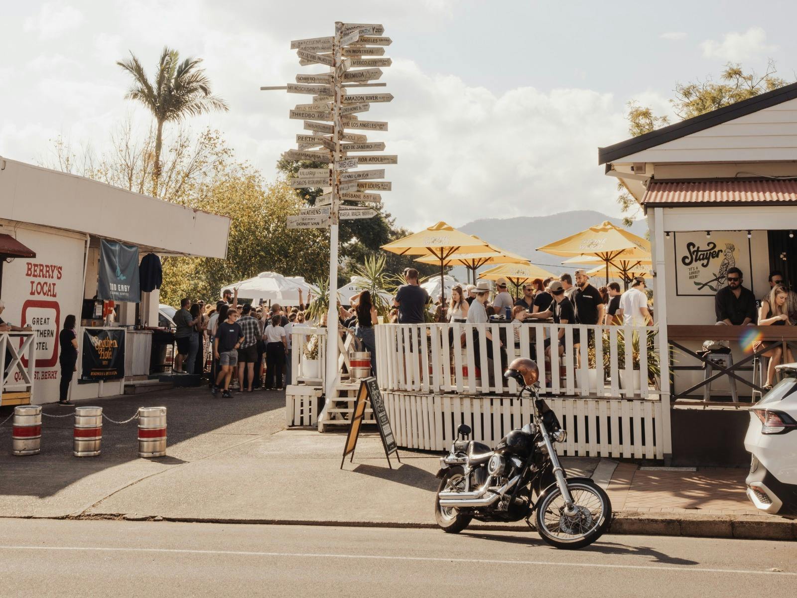 Exterior of Great Southern Hotel Berry showing the front deck with patrons seated under yellow umbre