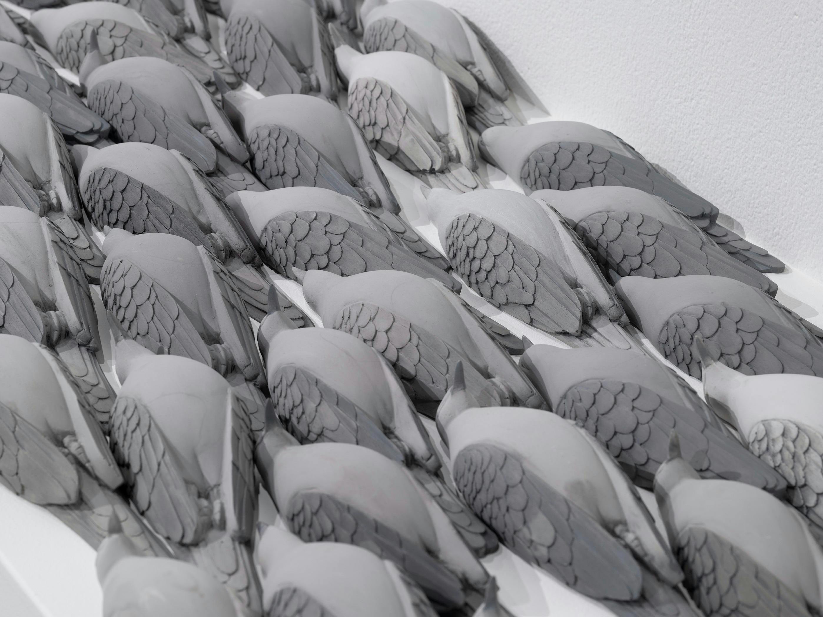 Realistic wooden scuplture of birds laying on their backs.